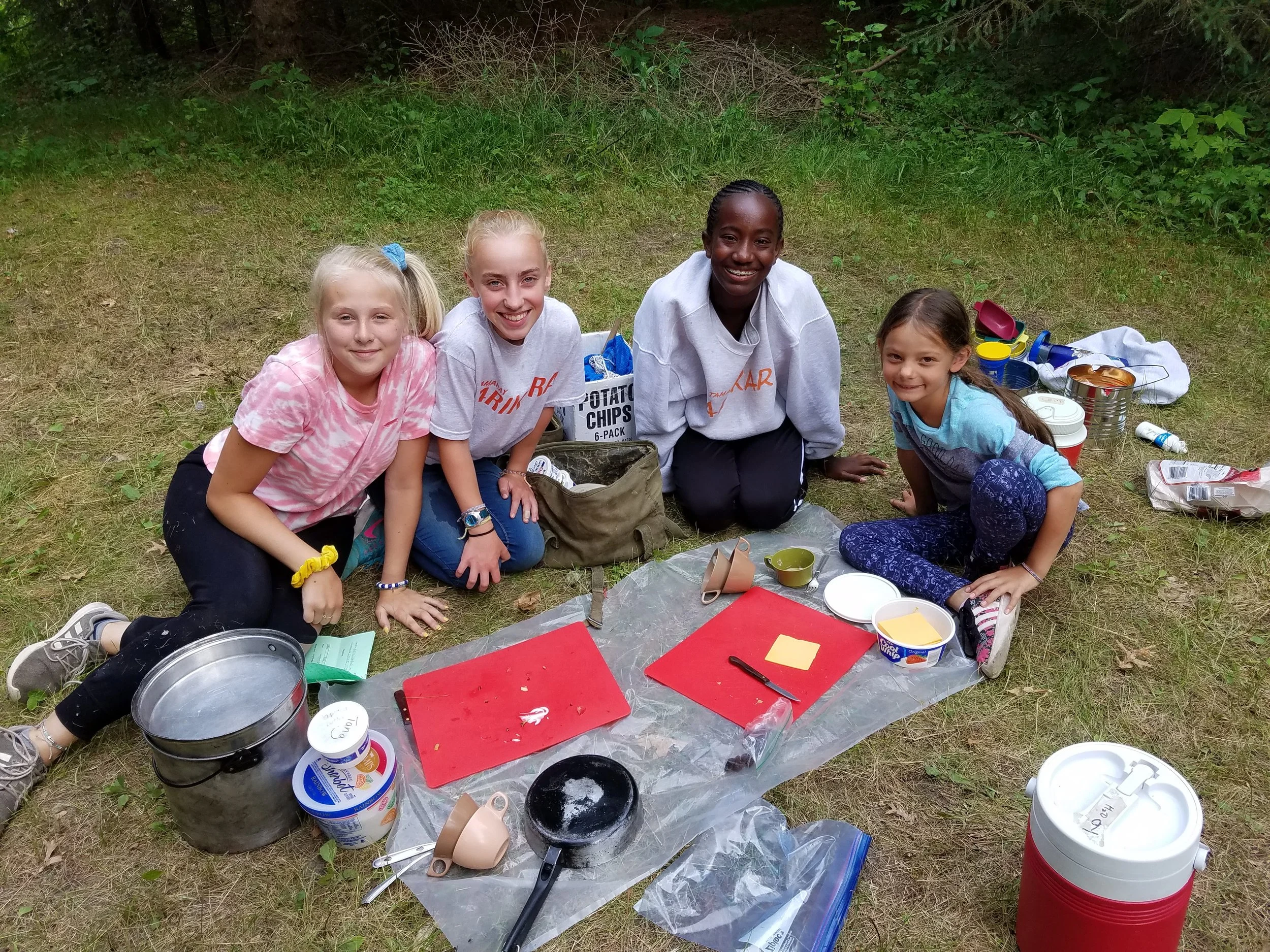 Four girls with cutting boards preparing food for cookout