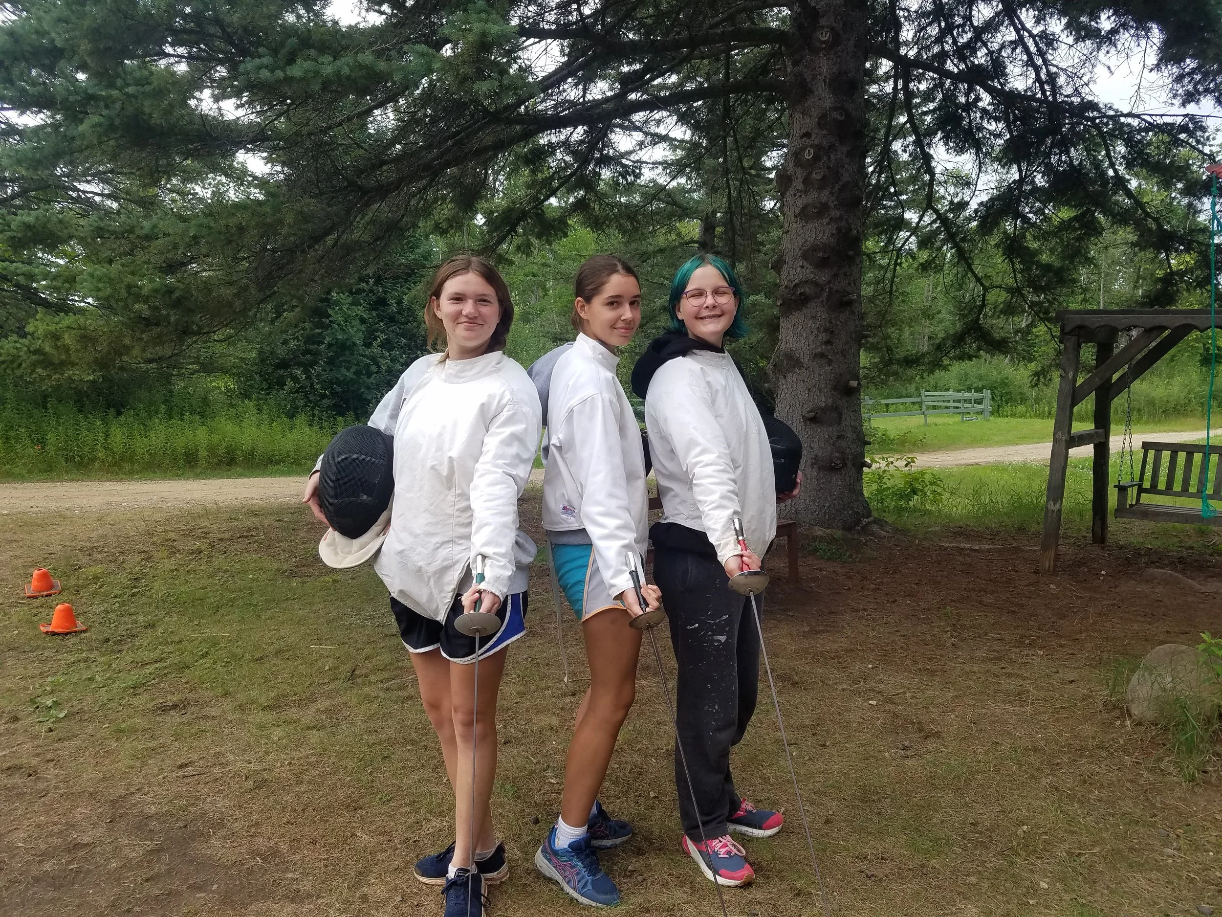 Three girls posing in fencing gear