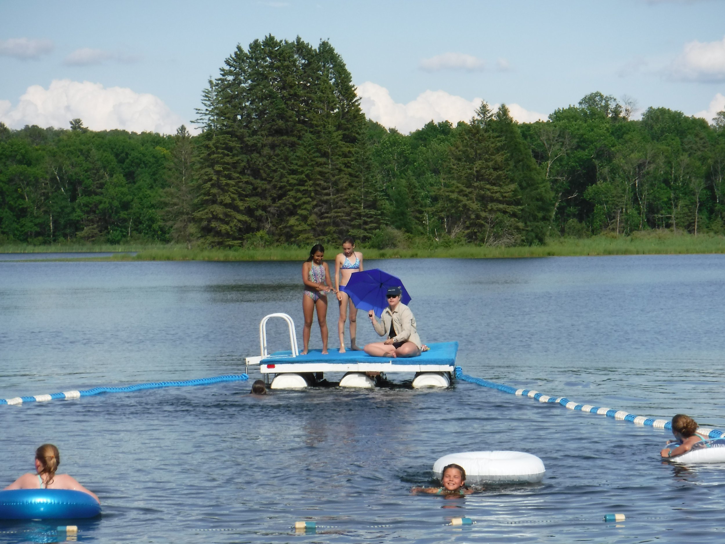 Swimmers in water and three girls on raft
