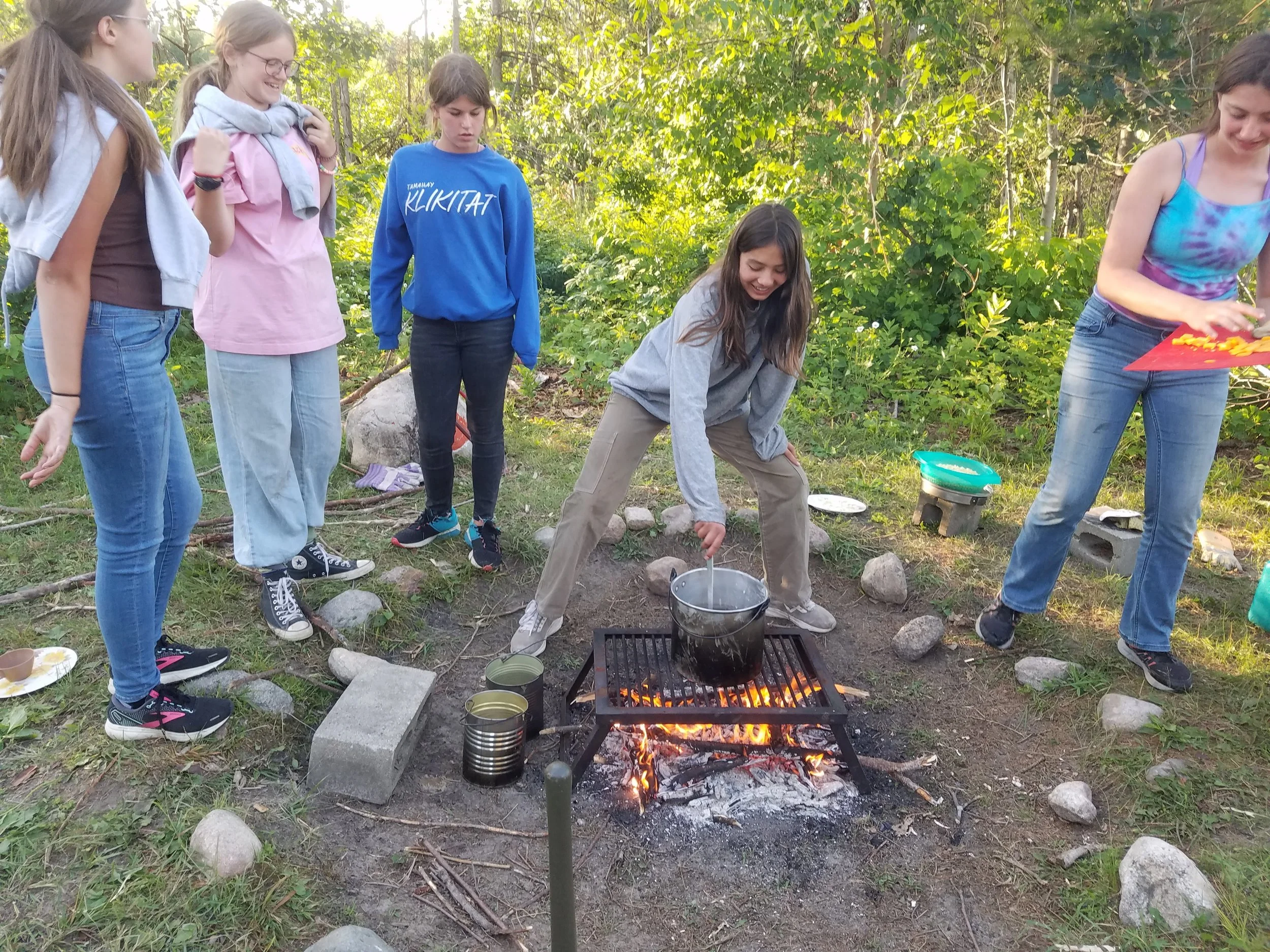 Five girls making mac and cheese over fire