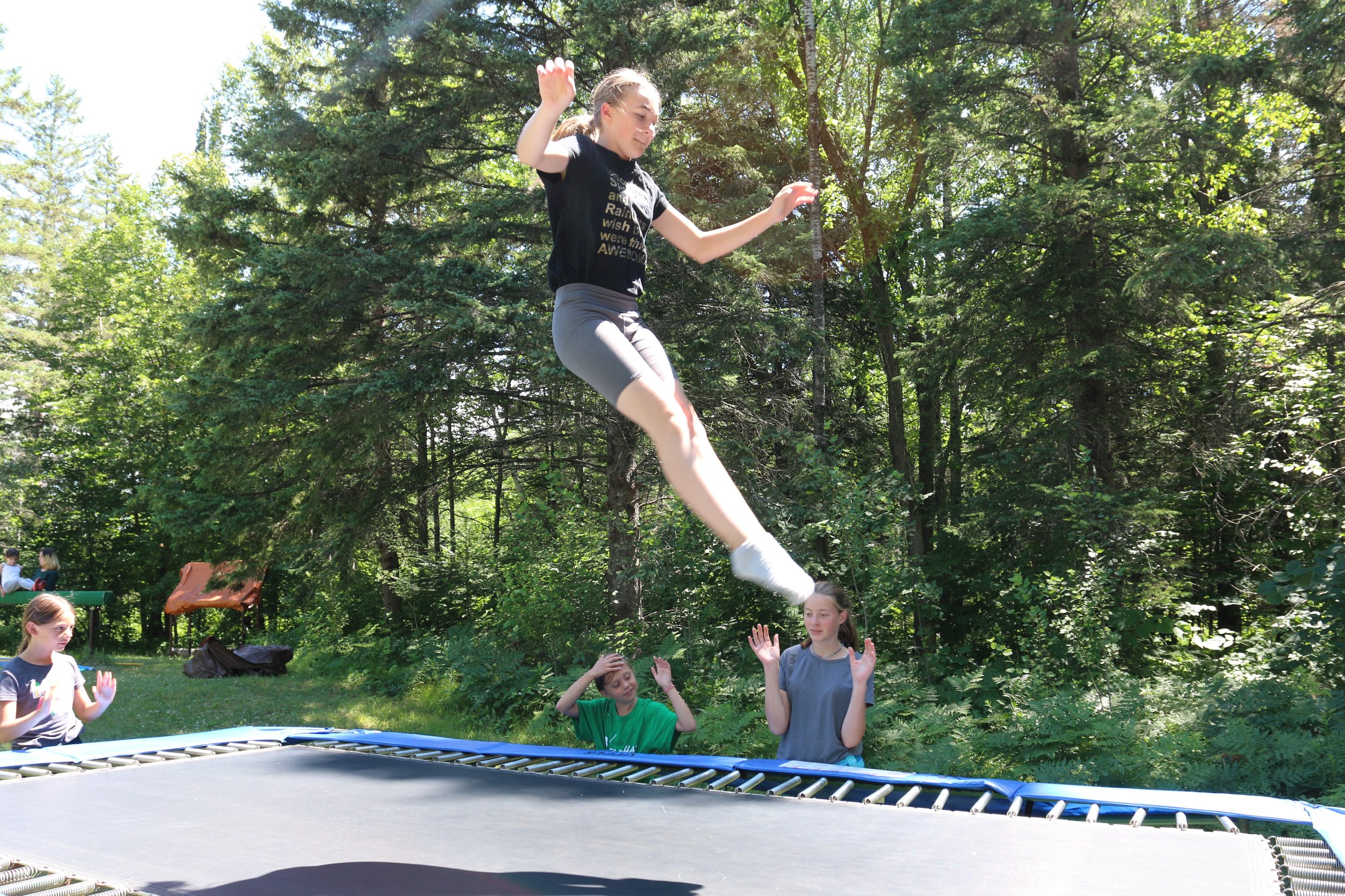 Jumping on trampoline with spotters in gymnastics.