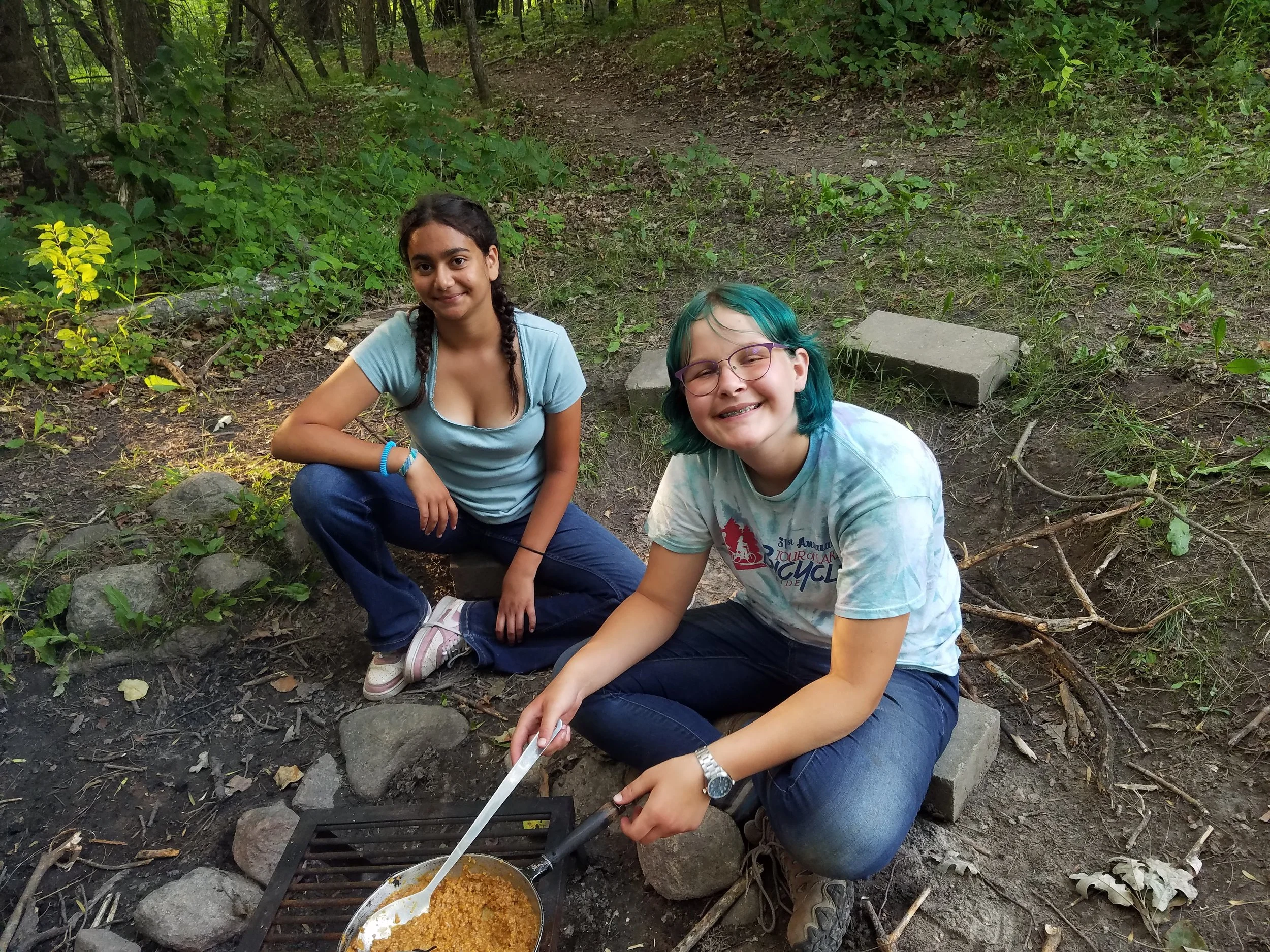 Two girls stirring food in frying pan
