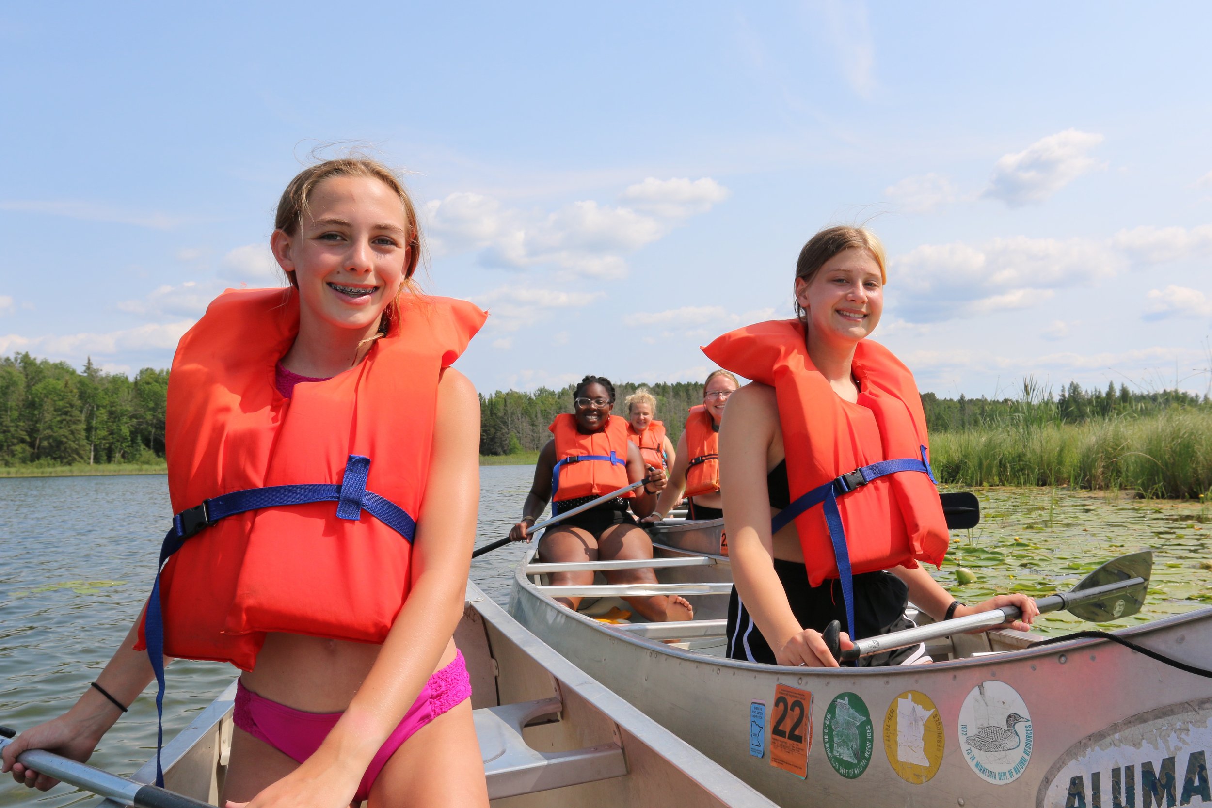 Three canoes on lake, pine trees behind