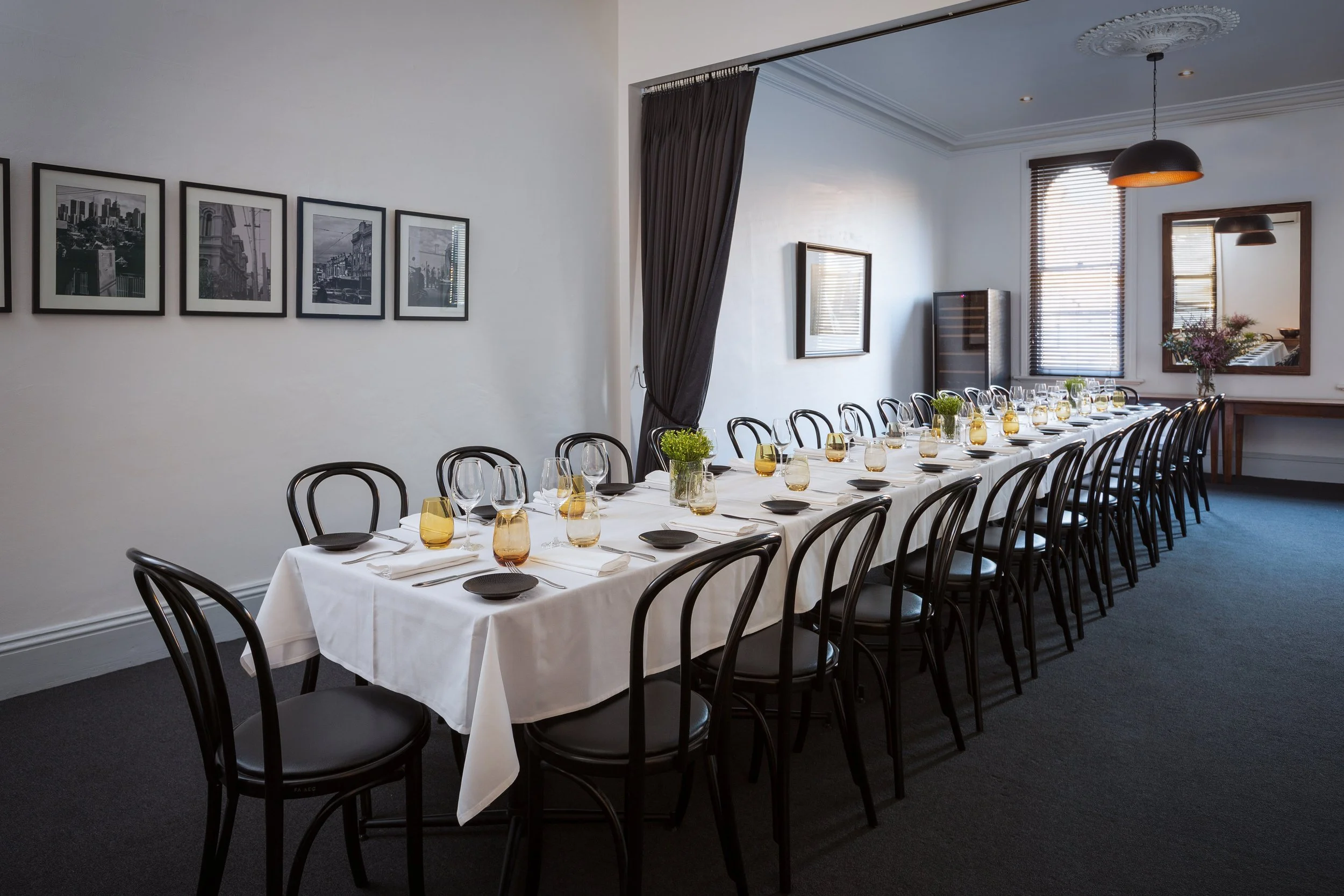Long dining table set in Estelle's private dining room with black and white framed photographs on the wall.