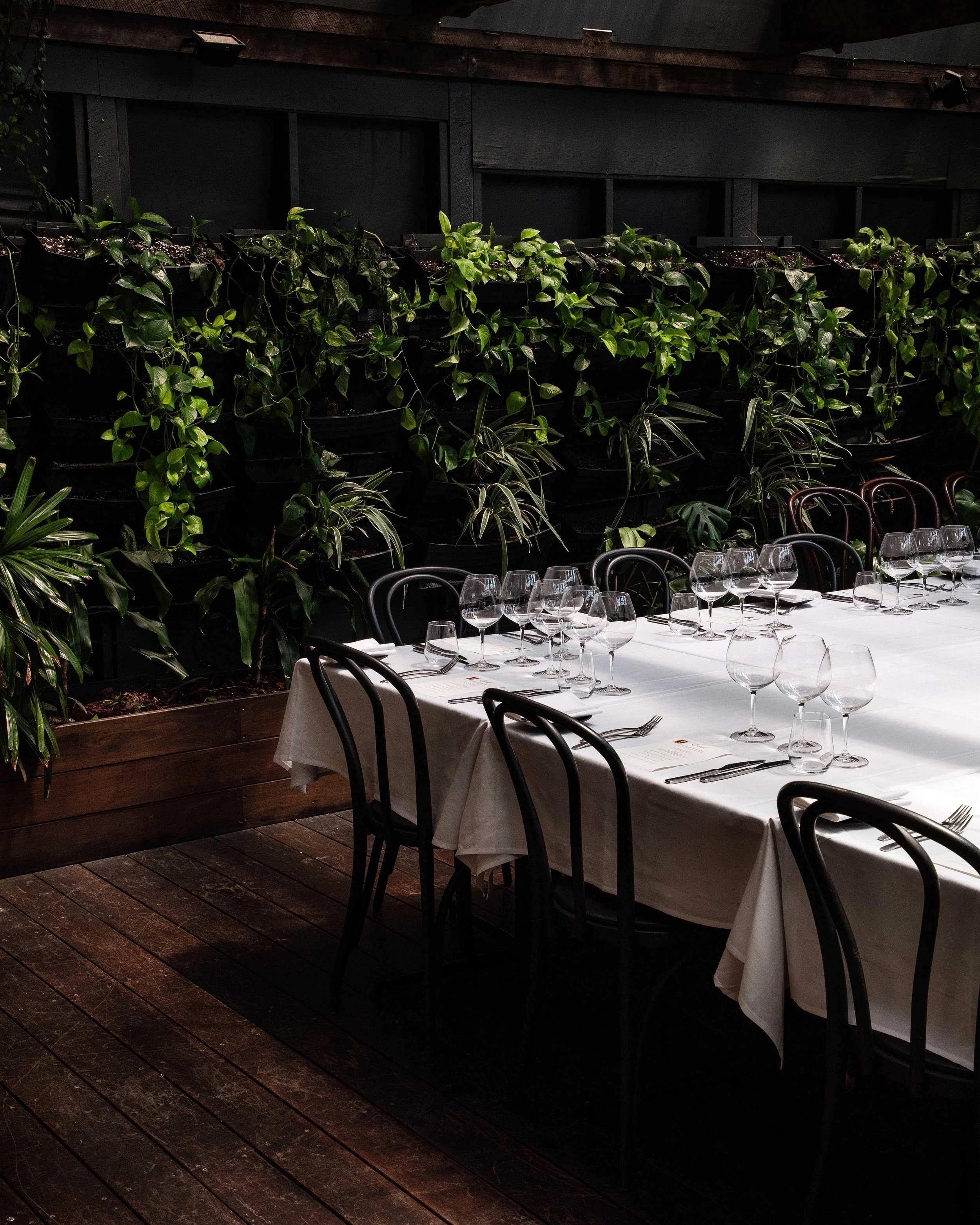 A dining table in Estelle's courtyard set with wine glasses, silverware, and a white tablecloth.