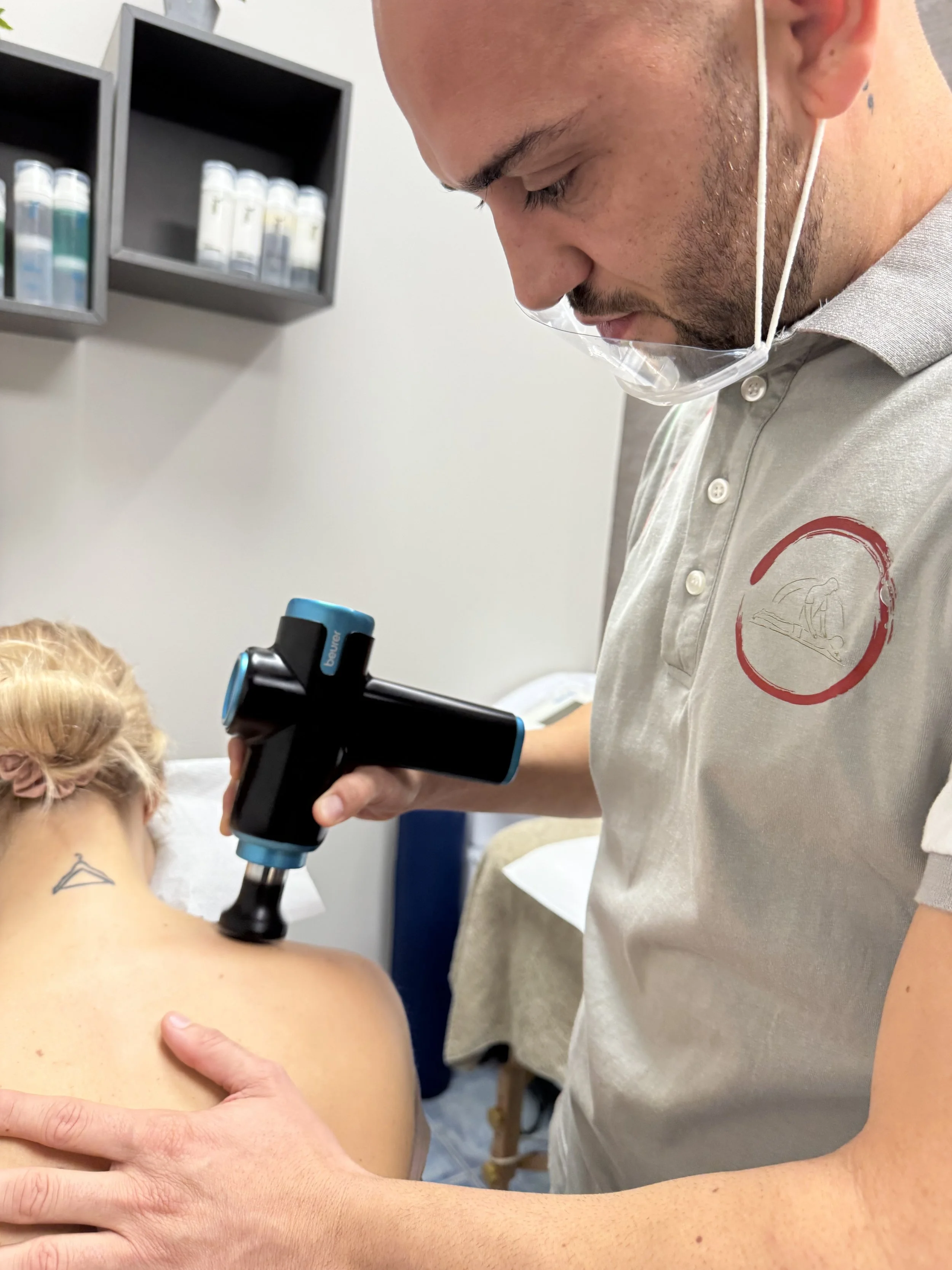 Un medico utilizza un apparecchio per la terapia sulla schiena di una paziente seduta su un lettino.