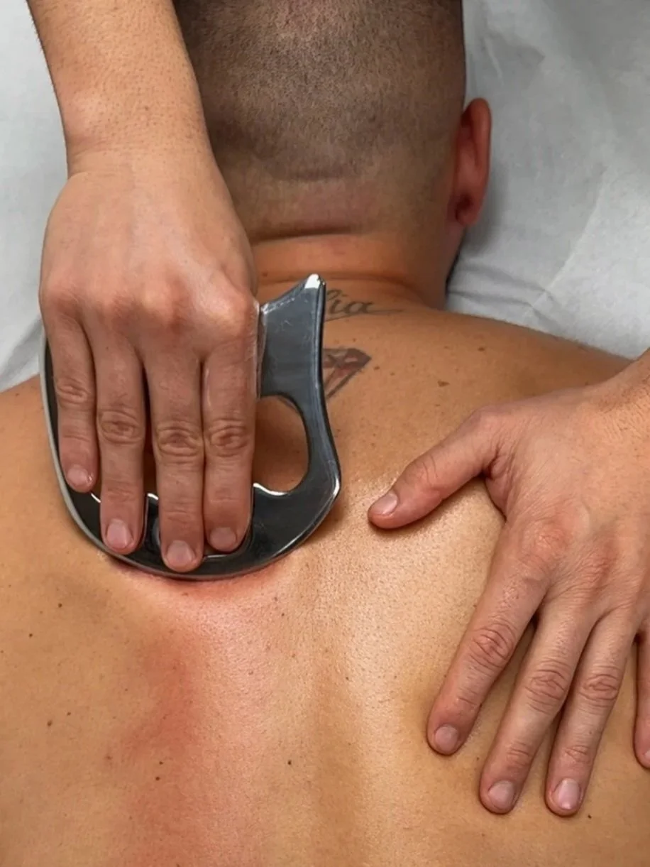 Una persona sta facendo una terapia con uno strumento appoggiato sulla schiena di un'altra persona durante un trattamento di massaggio o fisioterapia.