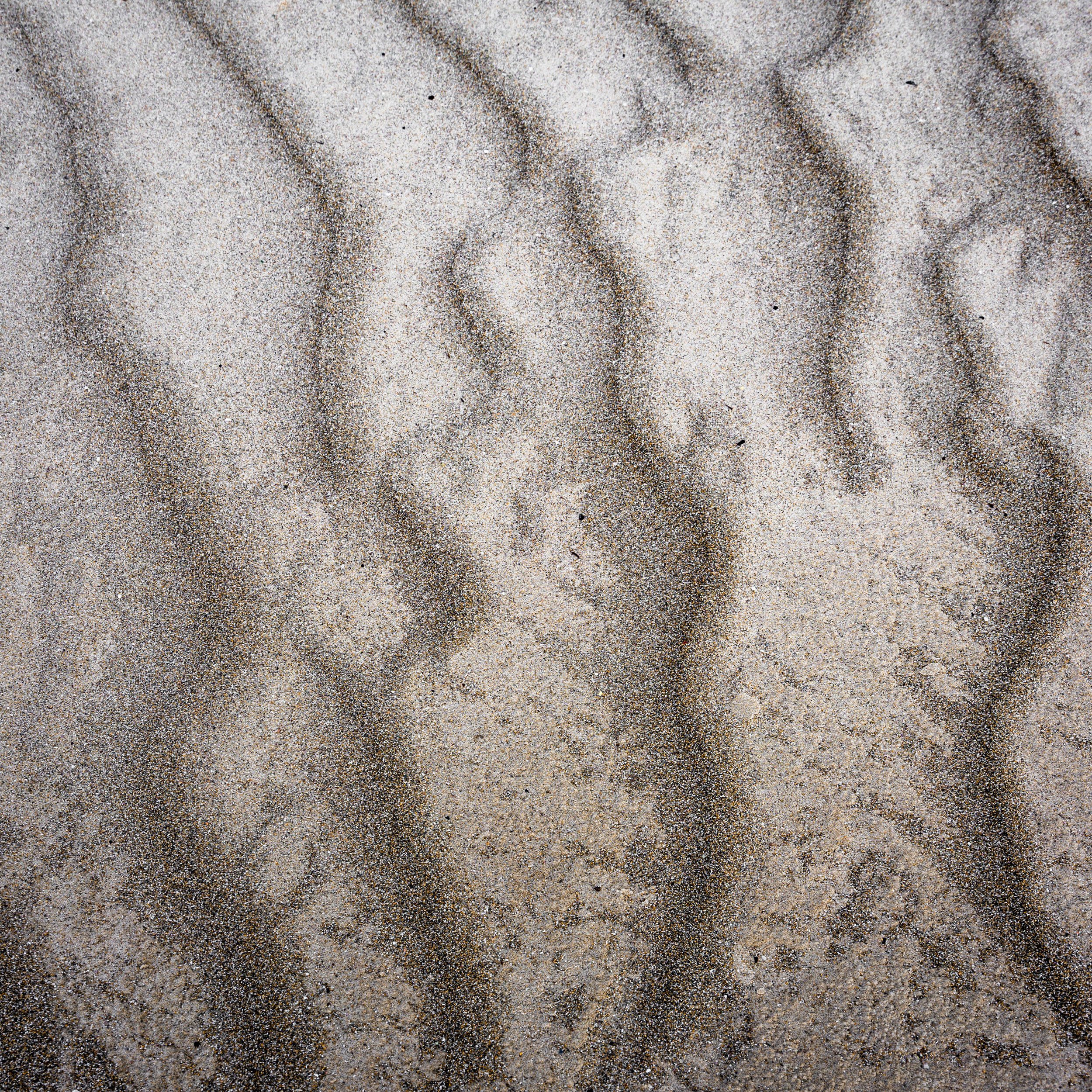 Close-up view of sand with textured patterns and footprints.