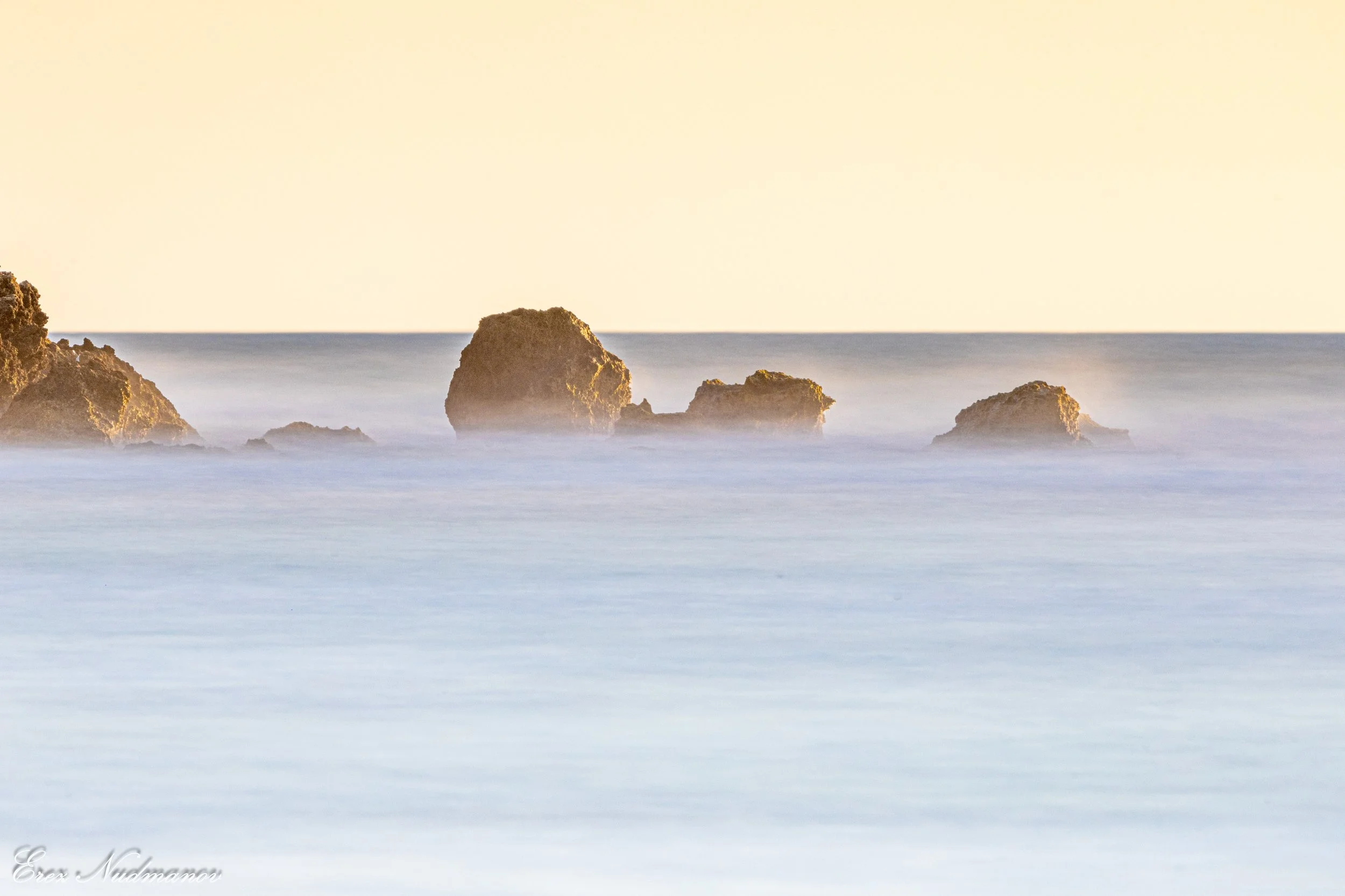 Sea with rocks and gentle waves during sunset or sunrise