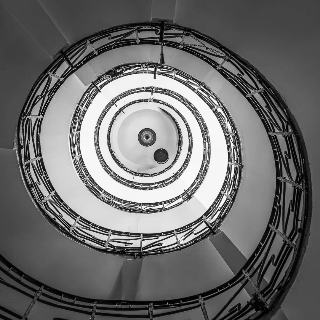 Black and white spiral staircase viewed from below, showing the circular handrails and steps.