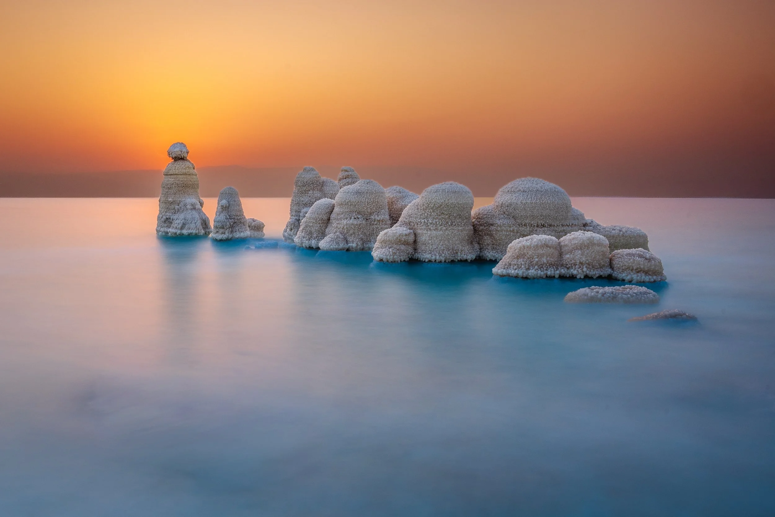 Salt formations rising from the ocean at sunset with a colorful sky
