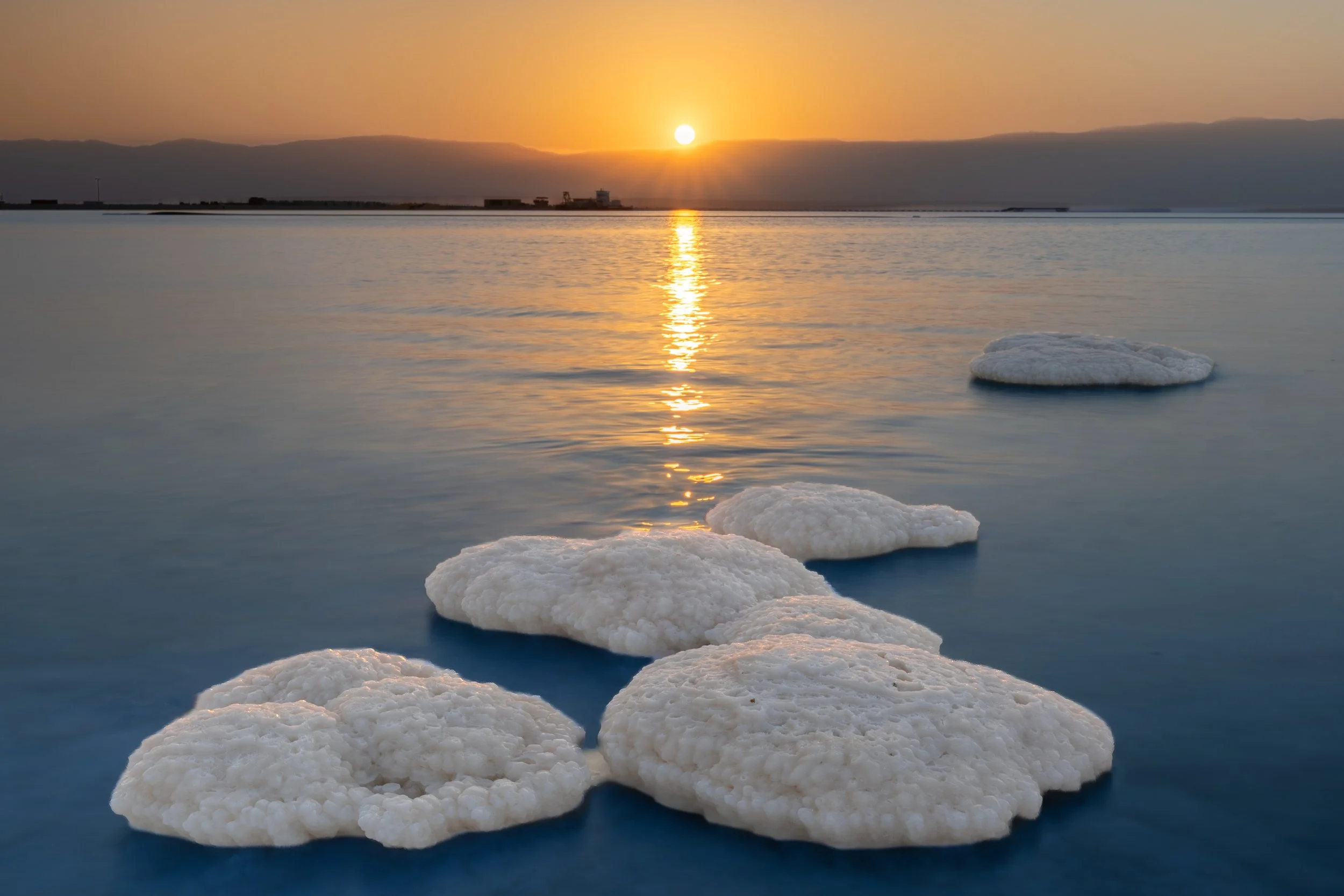 Salt flats with salt formations in shallow water at sunset.