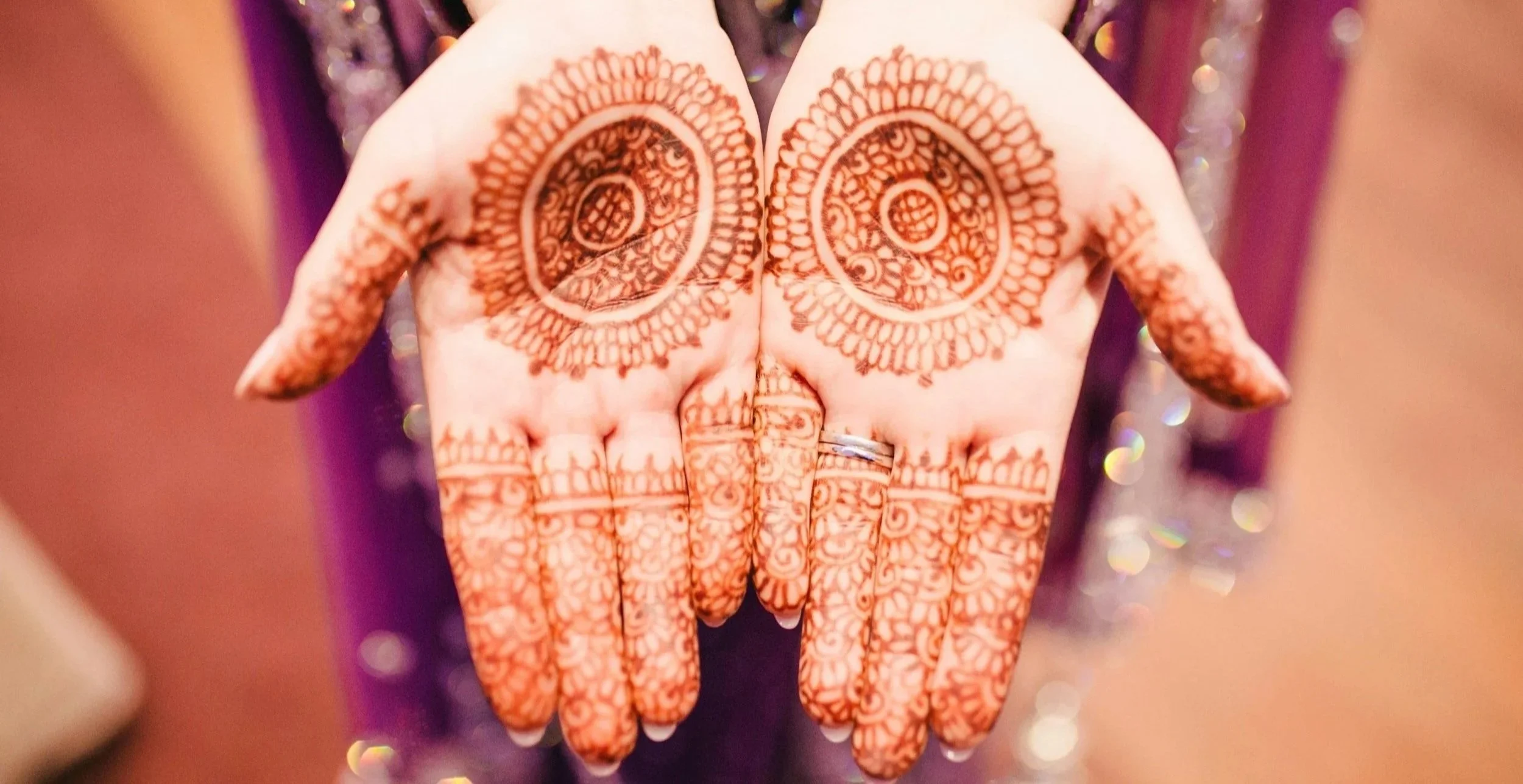 Hands held out with their palms open with a dyed pattern on them.