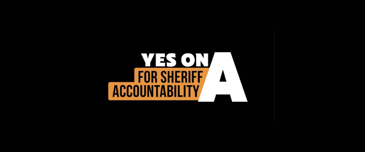 A political campaign sign with black background and white and orange text that reads, "YES ON A FOR SHERIFF ACCOUNTABILITY."