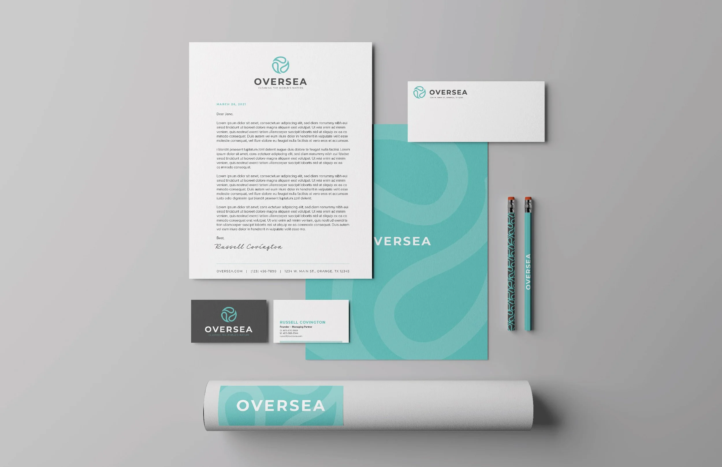 Branded stationery set for OVERSEA includes letterhead, business cards, envelopes, pens, and a rolled poster, all in a coordinated blue and white color scheme featuring a stylized circular logo.