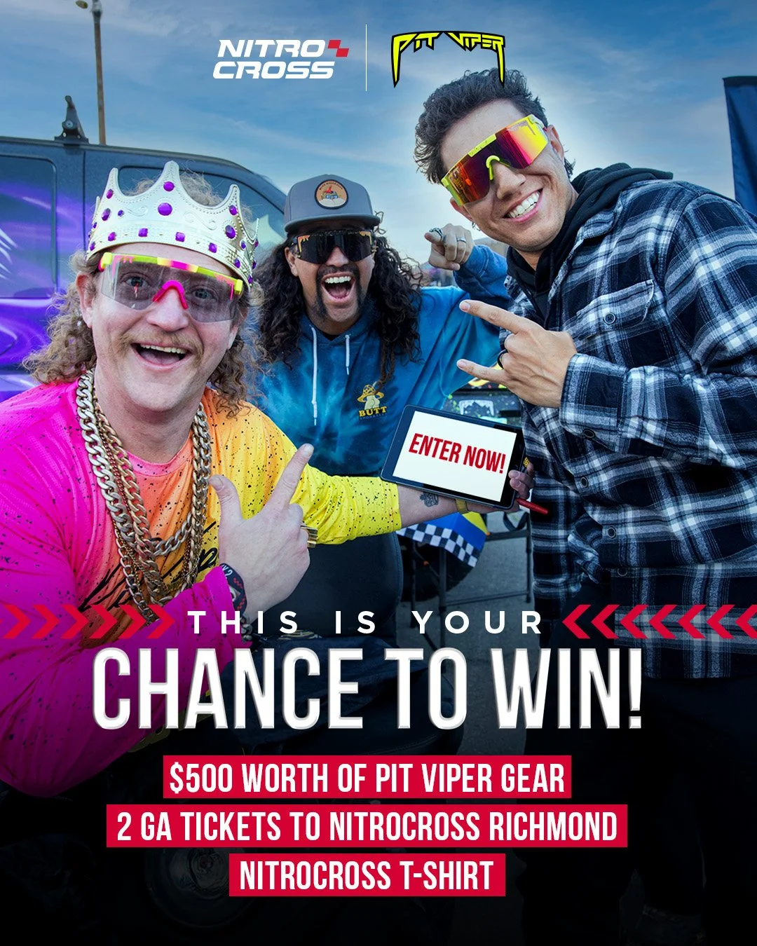 Three men smiling and celebrating at what appears to be a Nitro Cross event. One man wears a crown and vibrant clothing, another is in a blue hoodie, and the third sports sunglasses and a plaid shirt. They are pointing at a sign that says 'Enter Now!