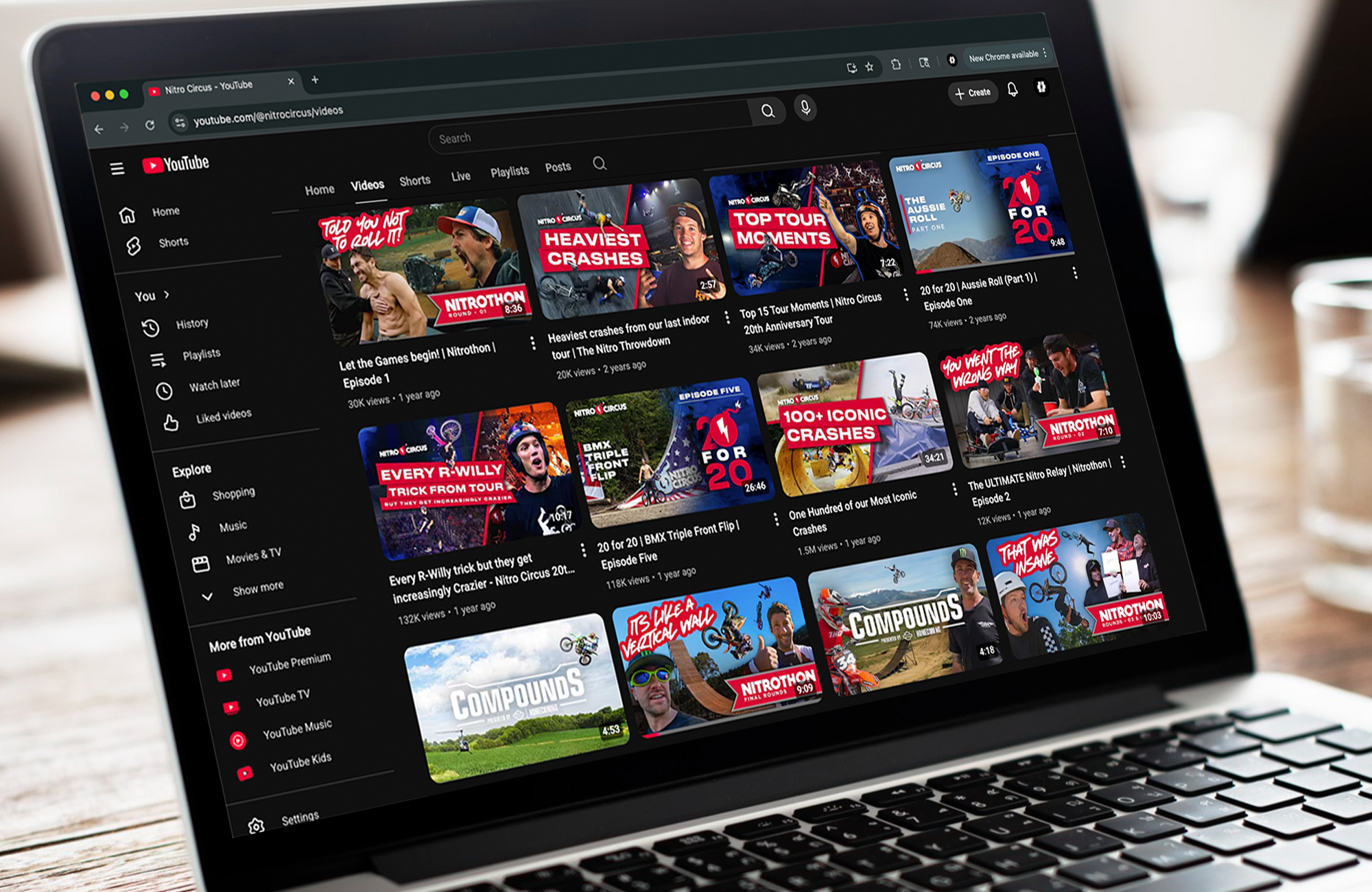 Laptop screen displaying a YouTube channel page with various videos related to Nitro Circus, including stunt tricks, crashes, and montages.