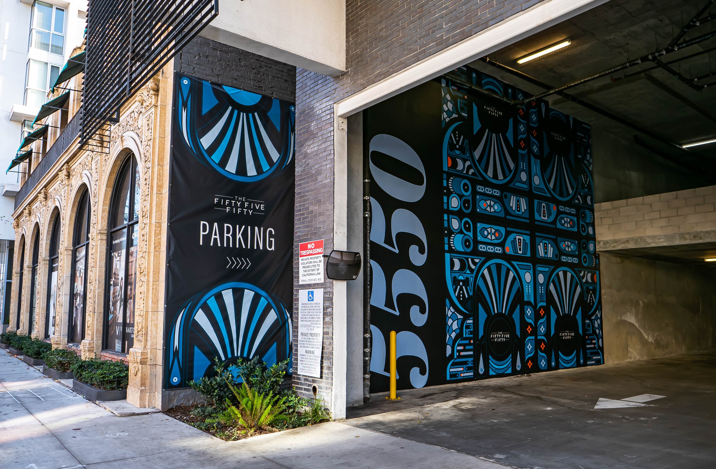 City parking garage entrance with vibrant blue and black mural art, a large 'PARKING' sign, and decorative architecture on the building exterior.