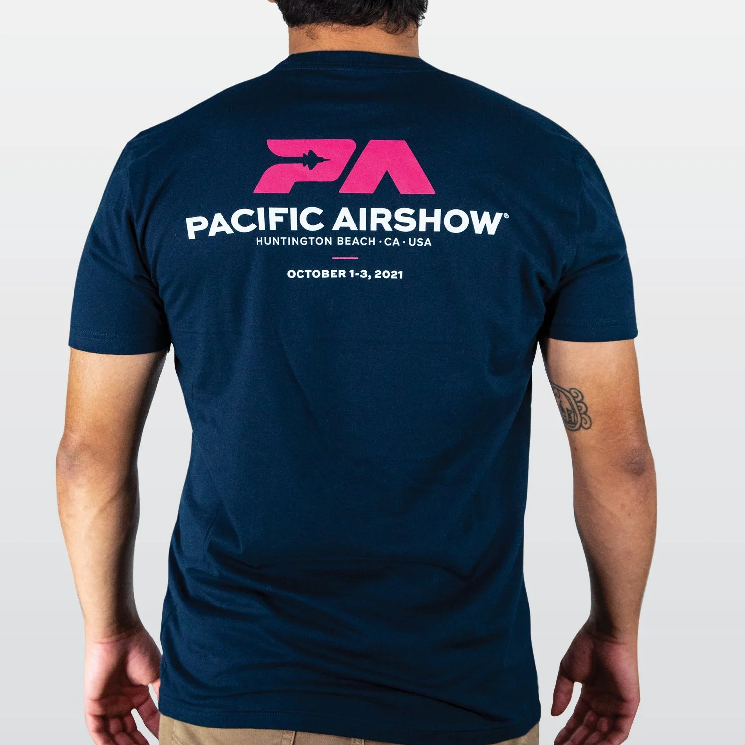 Back of a man wearing a navy blue T-shirt with a logo and text for the Pacific Airshow in Huntington Beach, California, October 1-3, 2021.