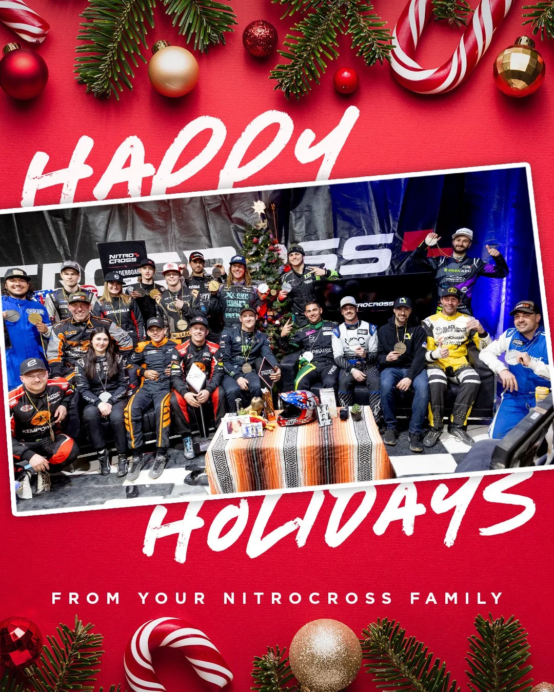 Group of NitroCross racers celebrating with medals and a Christmas tree, with holiday decorations on a red background.