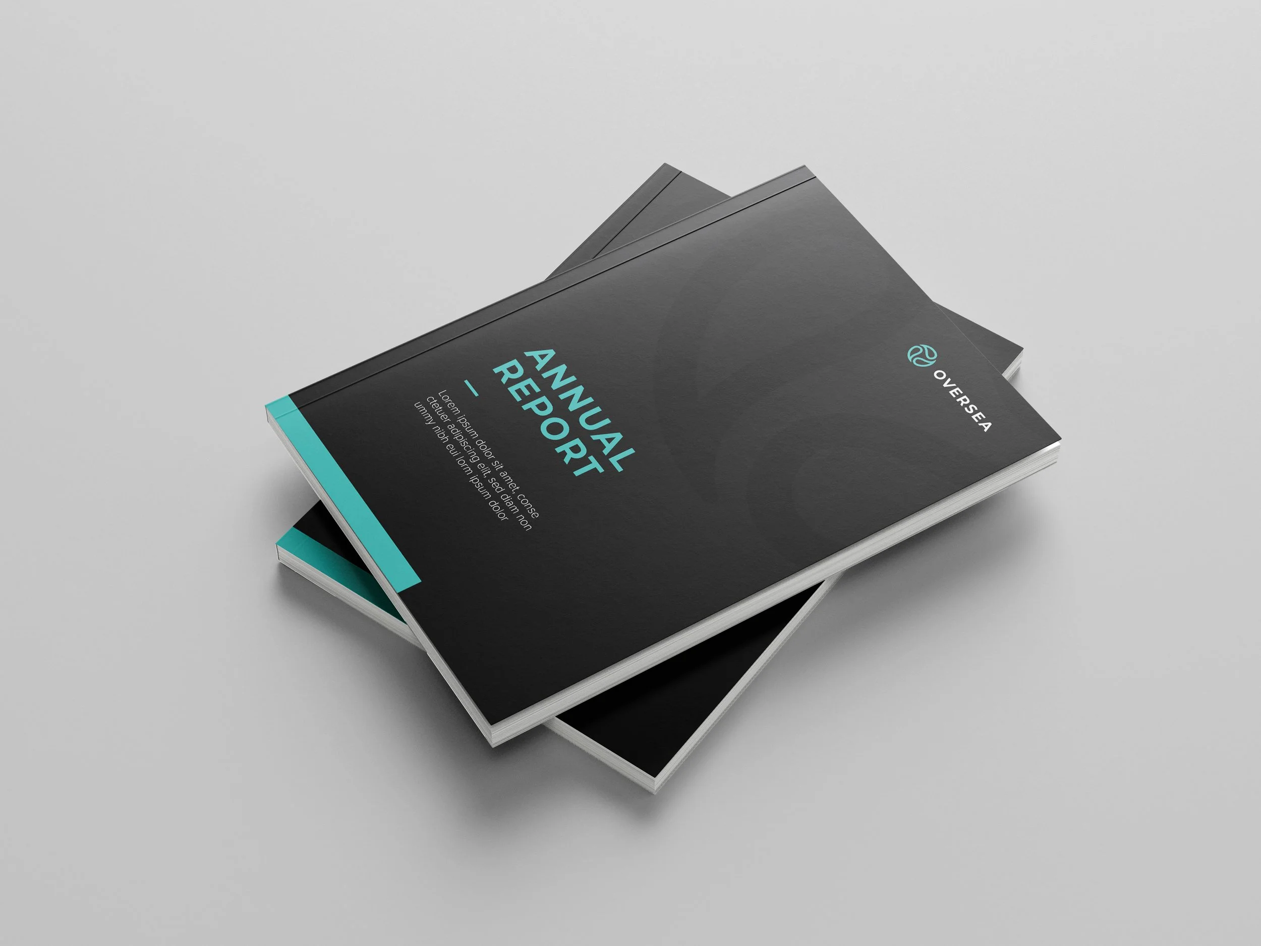 Two black hardcover books stacked, with the top book titled 'Annual Report' and a logo that reads 'OverSeA' in teal, on a light gray surface.