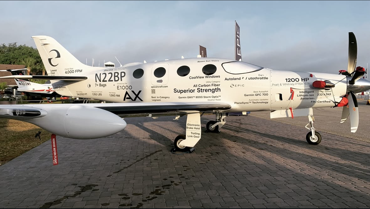 A small, white, twin-engine aircraft with various labels and specifications displayed on its exterior, parked on a brick tarmac.