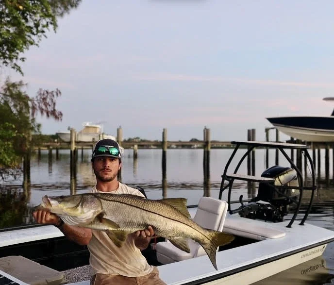 Man holding a large fish on a boat at a dock