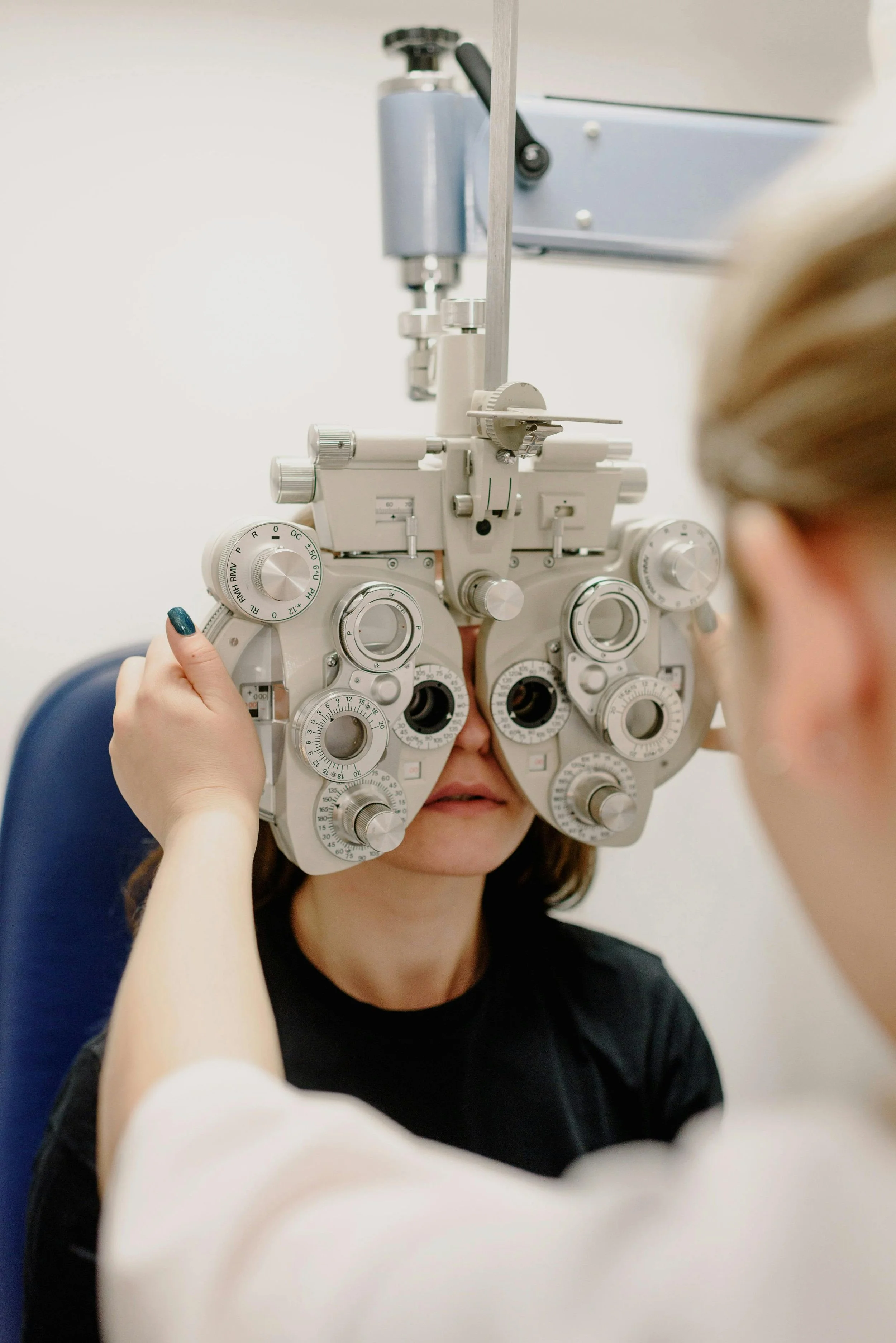Person undergoes an eye exam using a phoropter with multiple lenses to test vision.