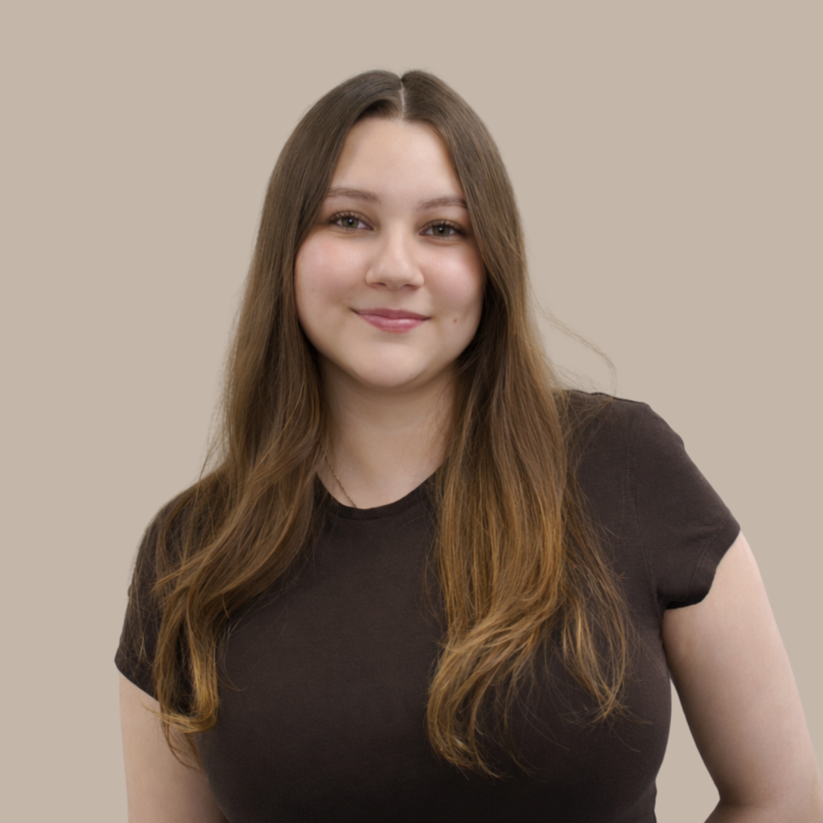Portrait of a young woman with long brown hair, wearing a black t-shirt, smiling lightly against a beige background.