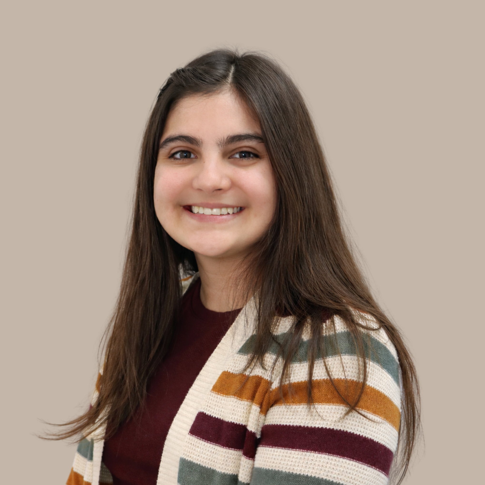 A young woman with long brown hair, smiling, wearing a striped cardigan over a maroon top, against a plain beige background.