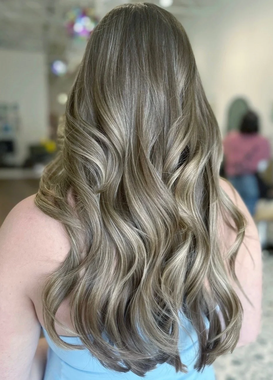 Long, wavy hair seen from behind with soft ash-blonde balayage over a darker brown base