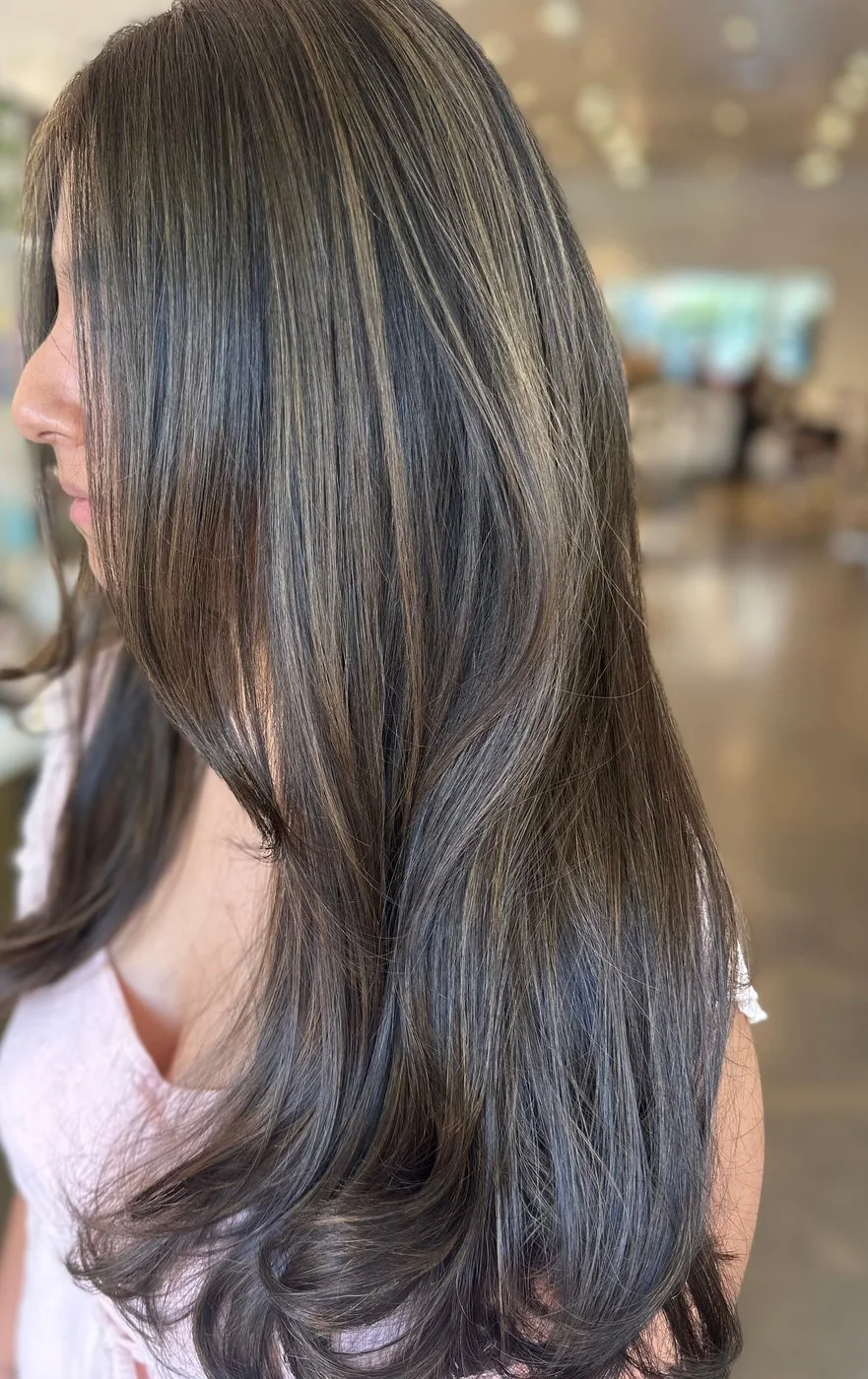 Side view of long, layered dark brunette hair with soft, low-contrast lighter brown balayage