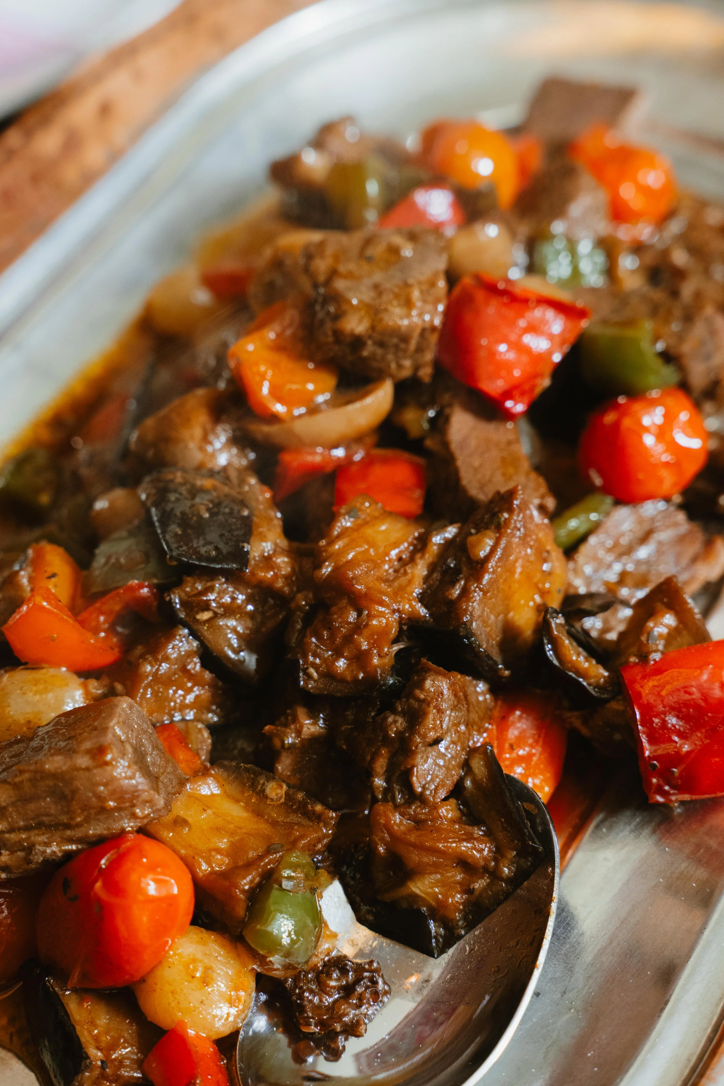 Beef stew with chunks of beef, carrots, potatoes, and bell peppers in a silver dish.