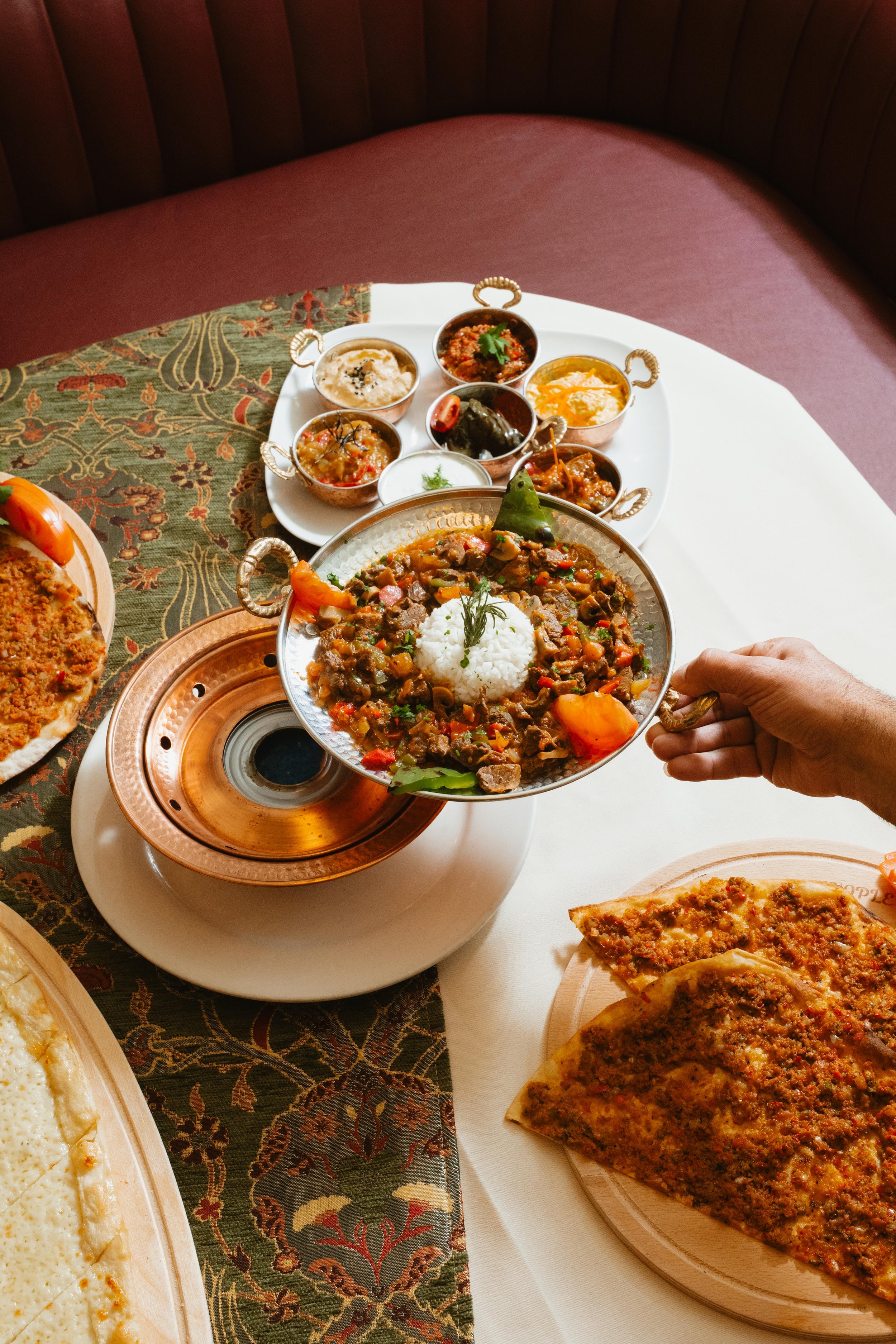 Indian dishes served on a table, including bowls of curries and a large plate of naan bread.