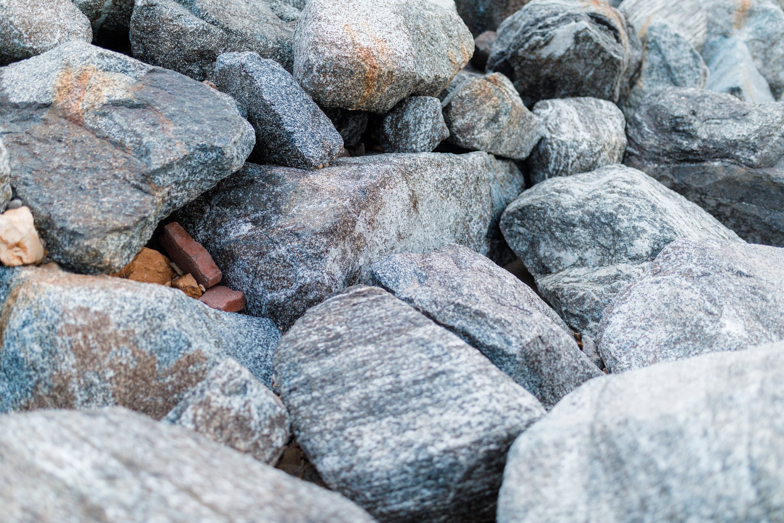 A close-up view of a collection of various-sized gray and brown rocks and stones.