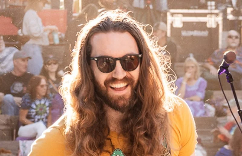Guitarist in sunglasses grinning on stage