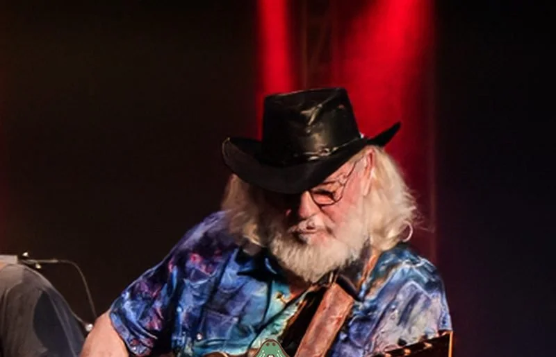 Guitarist in a black hat playing acoustic