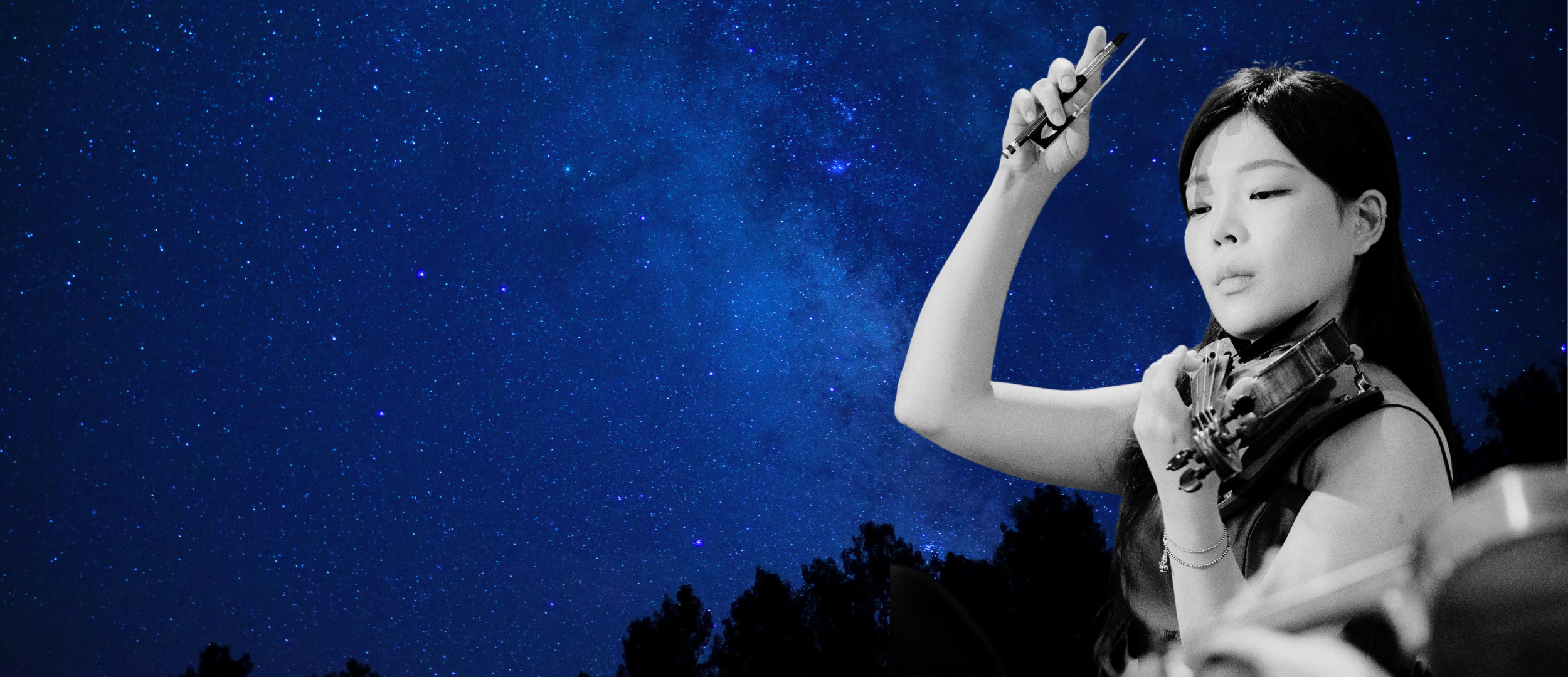 A young woman playing the violin under a starry night sky.