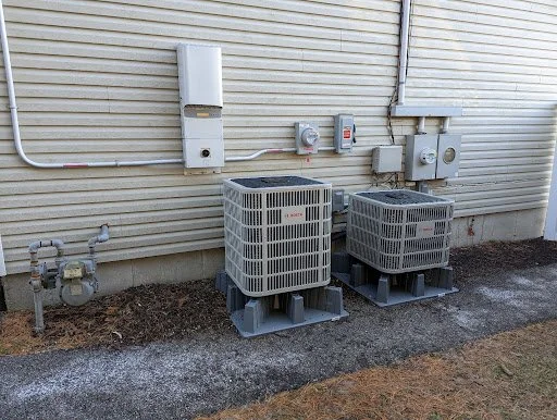 Two outdoor air conditioning units installed on the side of a home