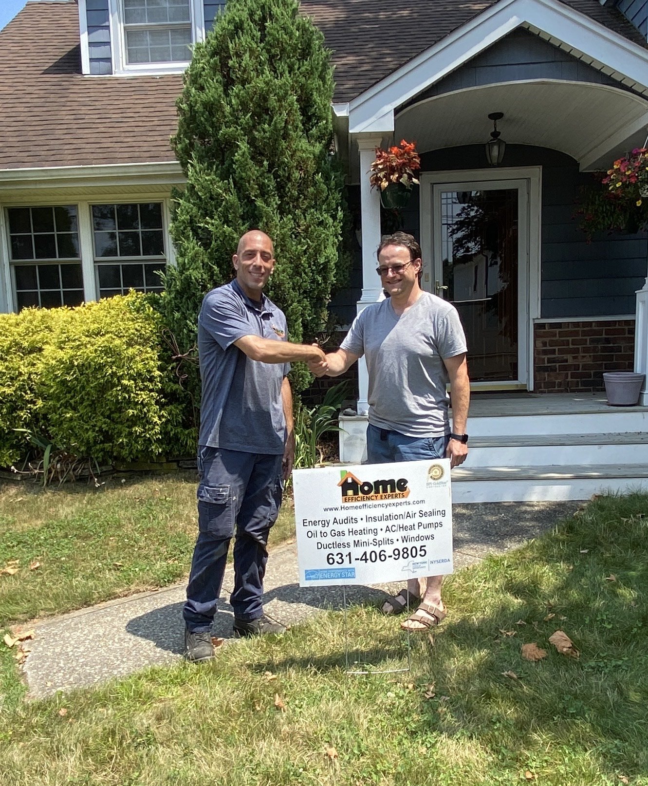 Two men shaking hands in front of a house, standing next to a sign for Home Efficiency Experts.