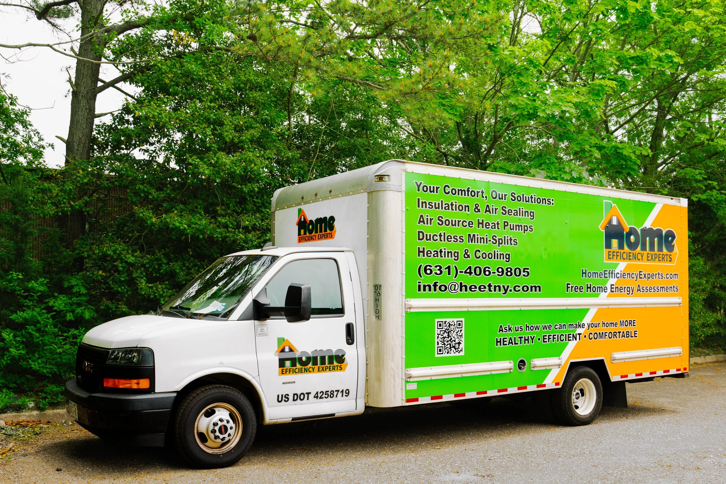 Home Efficiency Experts service truck outside with greenery behind it