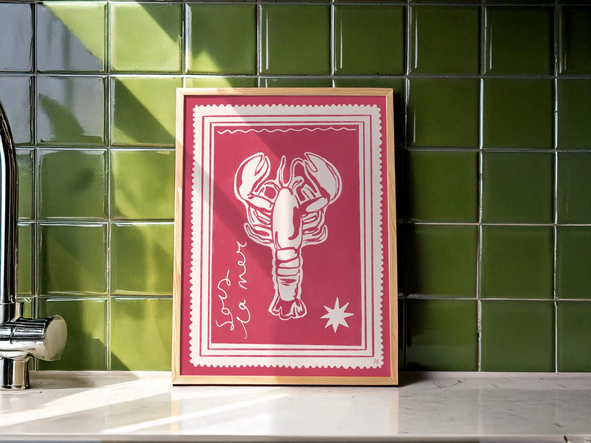 Framed print featuring a bold pink background and stamp-style illustration of a lobster with the text ‘Sous La Mer'.