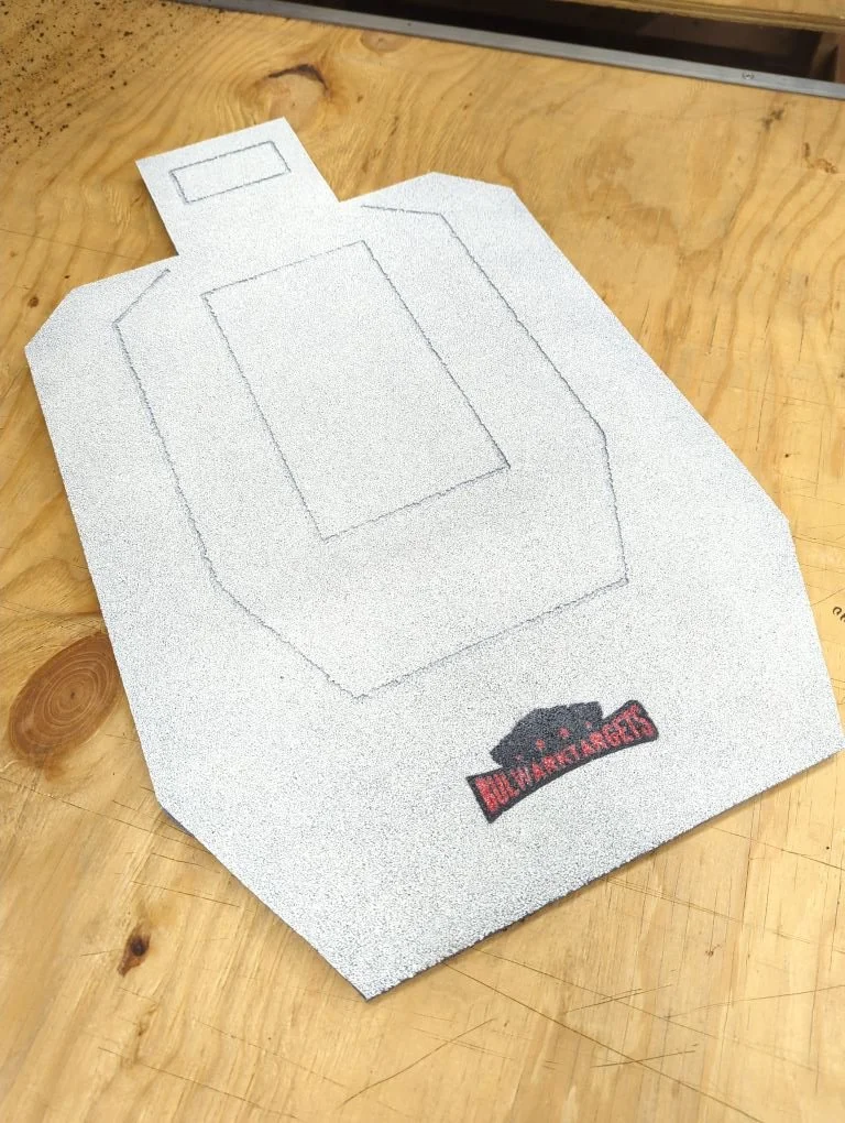 A textured white training pad with a black and red logo that reads 'DOG MANUFACTURERS', placed on a wooden surface.