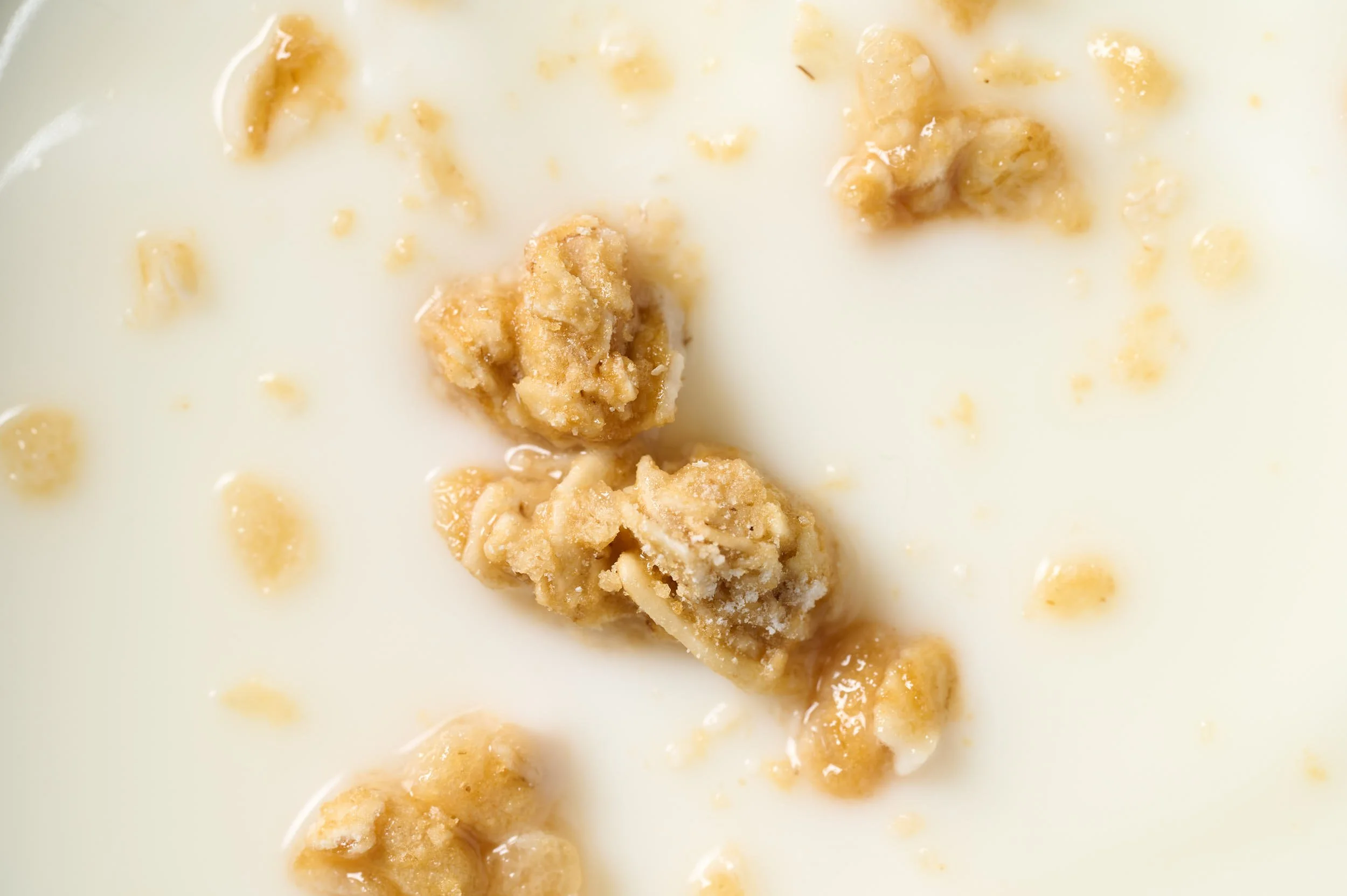 Close-up of a bowl of milk with chunks of cookie dough and bits of cookie scattered on top.