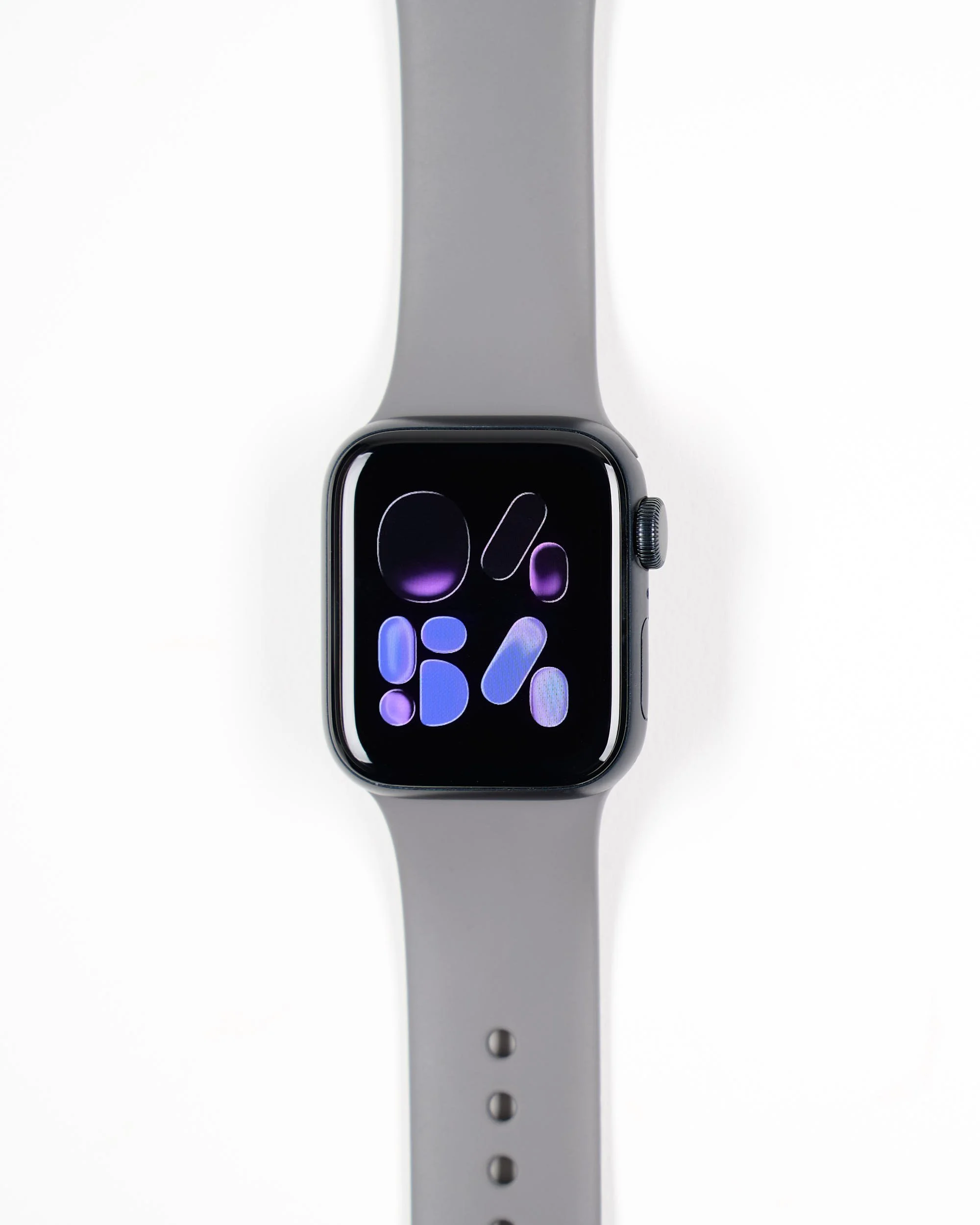 A smartwatch with a gray band displaying a colorful abstract design on the screen, placed on a white background.
