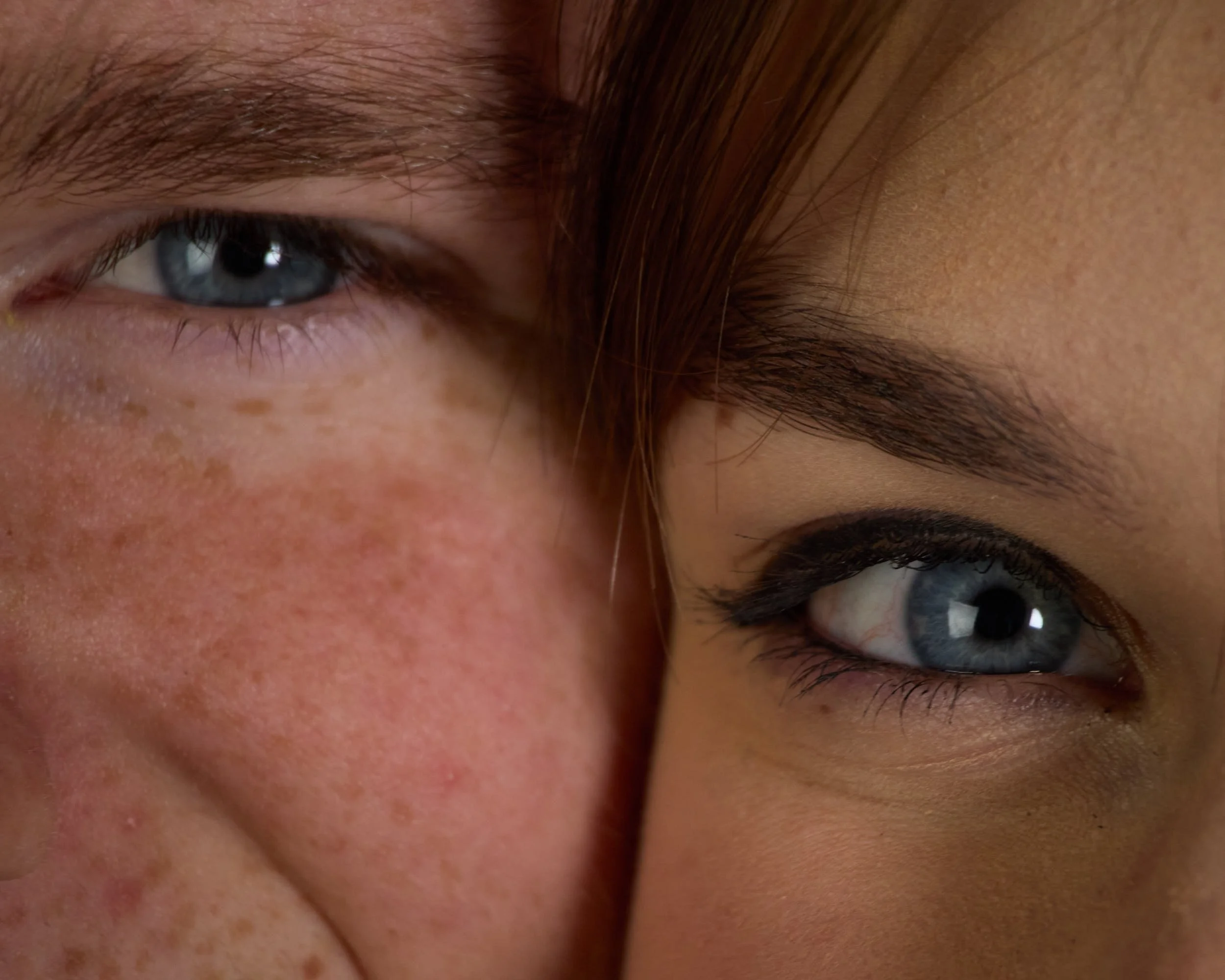 Close-up of the eyes and part of the faces of two people, one with fair skin and the other with darker skin, showing detailed textures and features.