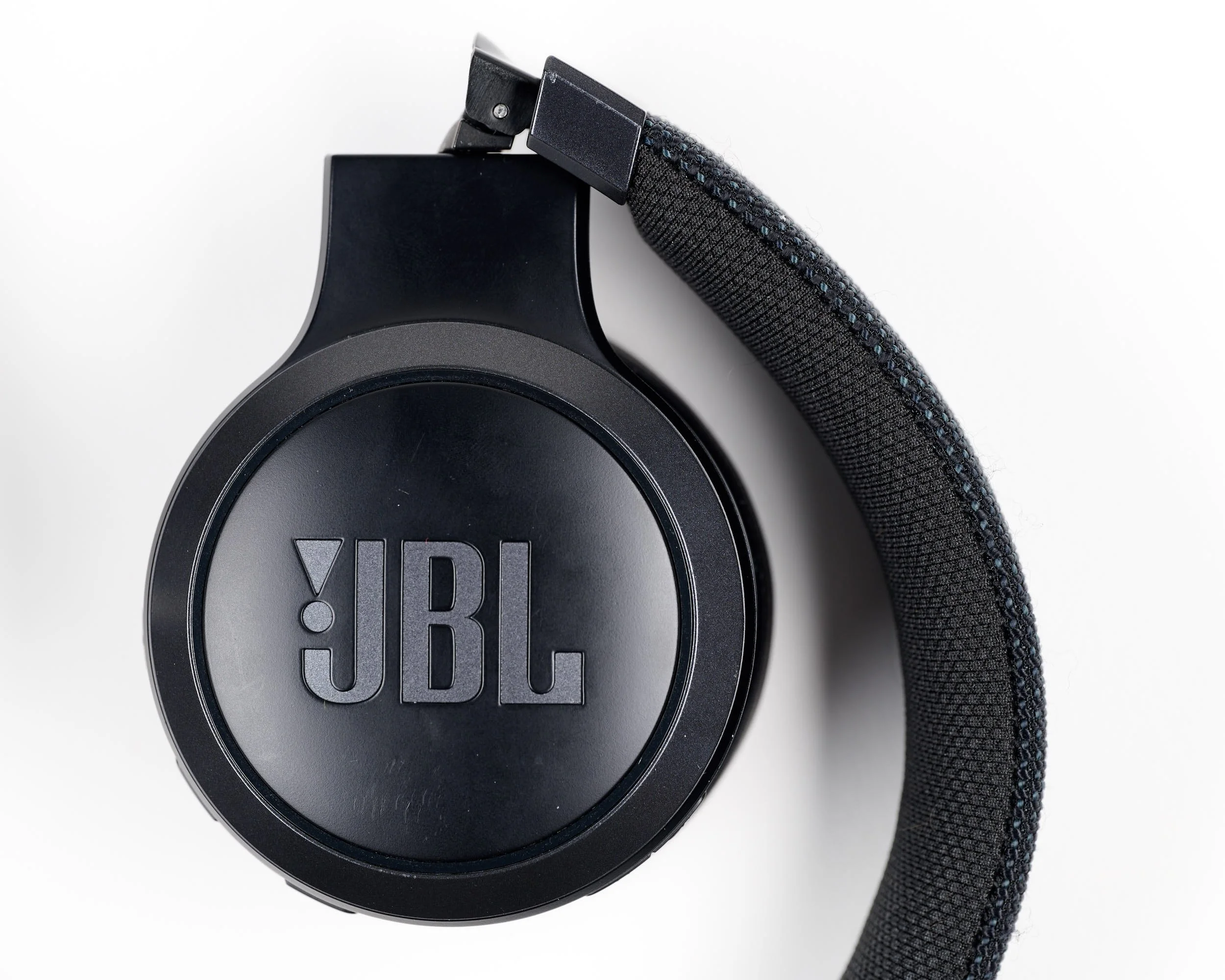Black JBL over-ear headphones with textured headband resting on a white surface.