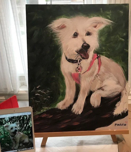 Painting of a white dog with a pink harness sitting on a log, with a photo of the same dog displayed on a nearby tablet.