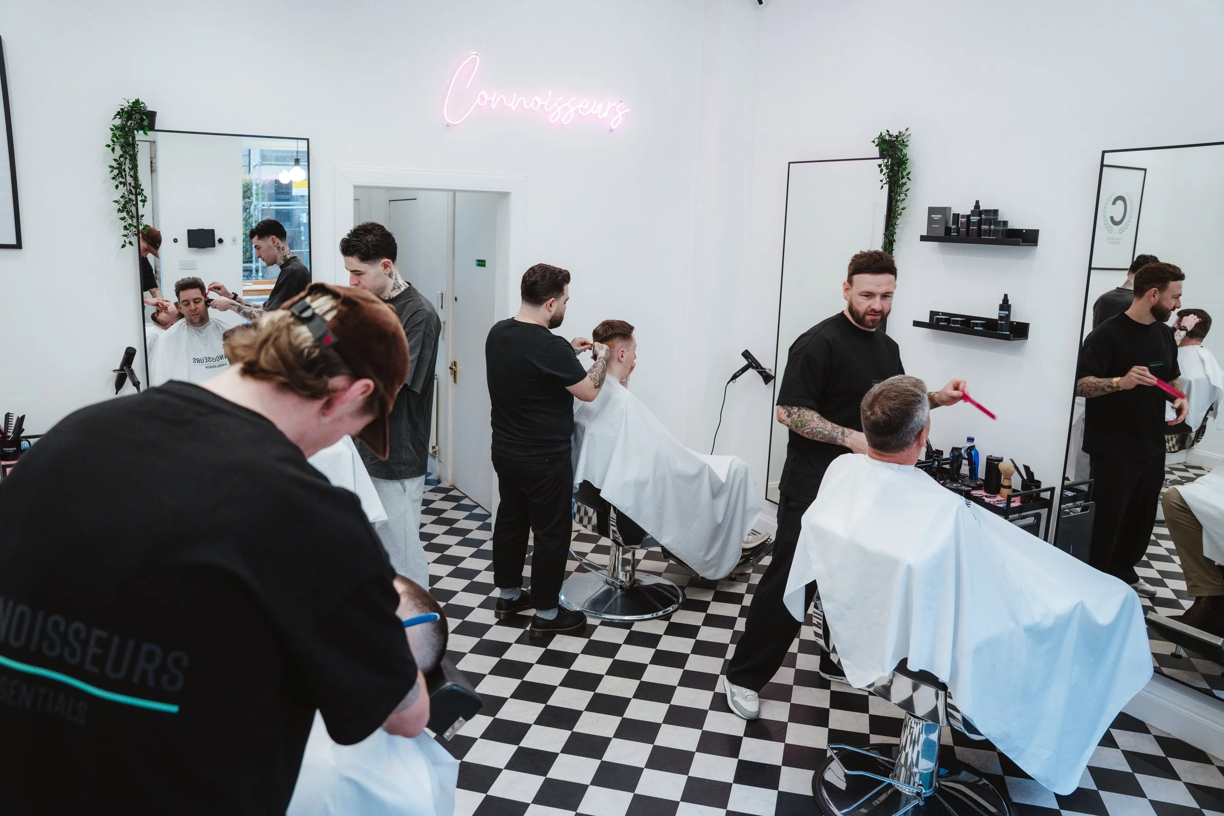 Busy barbers working with clients at Connoisseurs Barbershop in Leith, Edinburgh