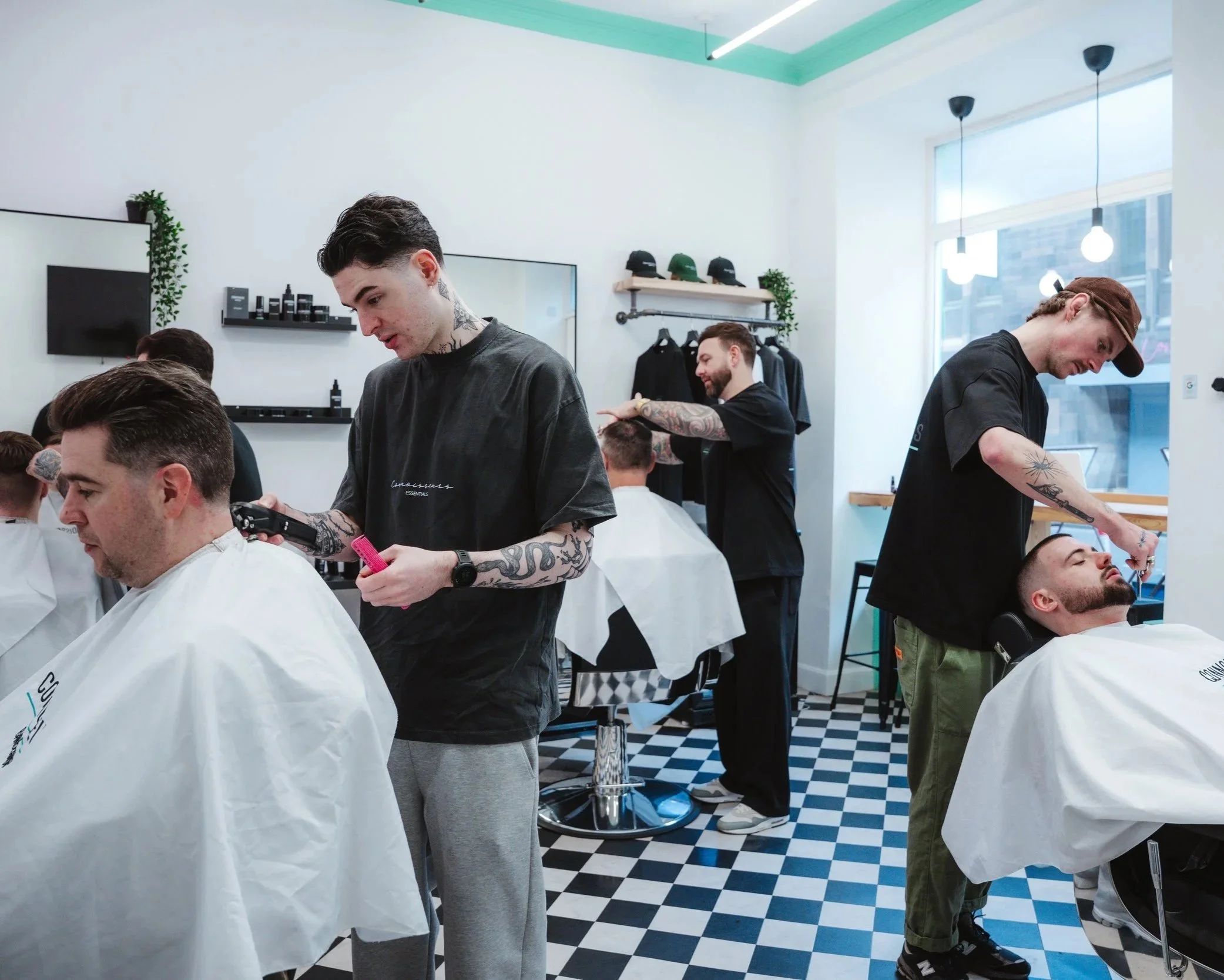 Barbers cutting hair inside Connoisseurs Barbershop in Leith, Edinburgh